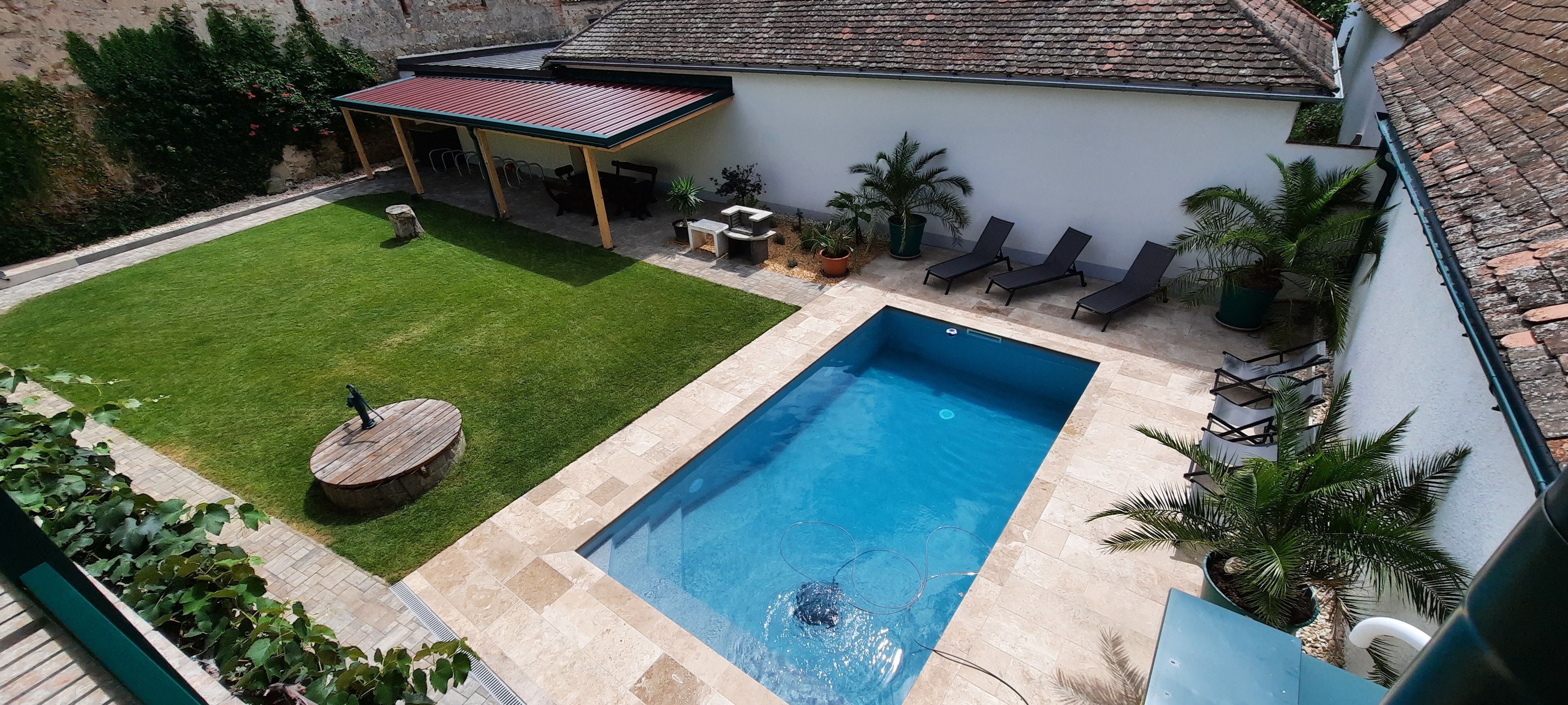 Garten mit Pool, Liegestühlen und überdachter Terrasse.