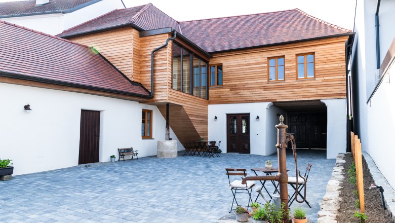 Innenhof eines Gästehauses mit Holzelementen und gepflastertem Boden.