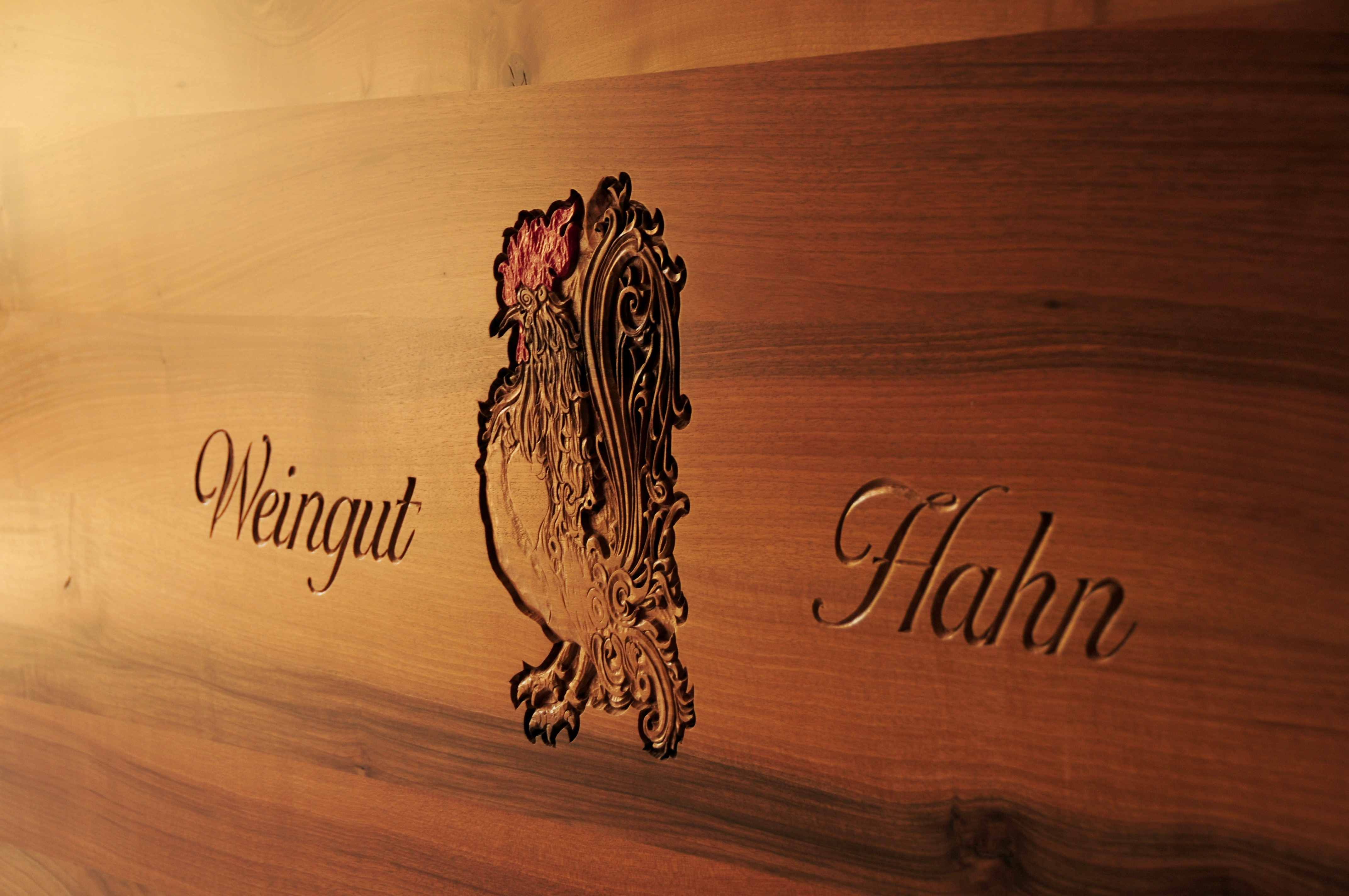 Dřevěná deska s vyrytým kohoutem a nápisem "Weingut Hahn".