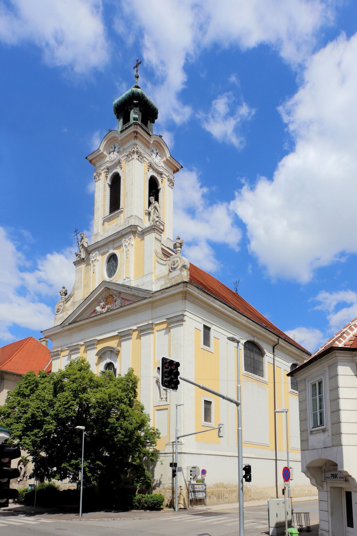 Barocke Kirche mit Turm und Uhr vor blauem Himmel.