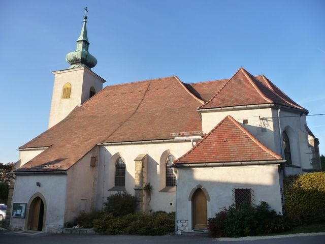 Eine historische Kirche mit einem roten Ziegeldach und einem kleinen Turm mit grünem Dach.