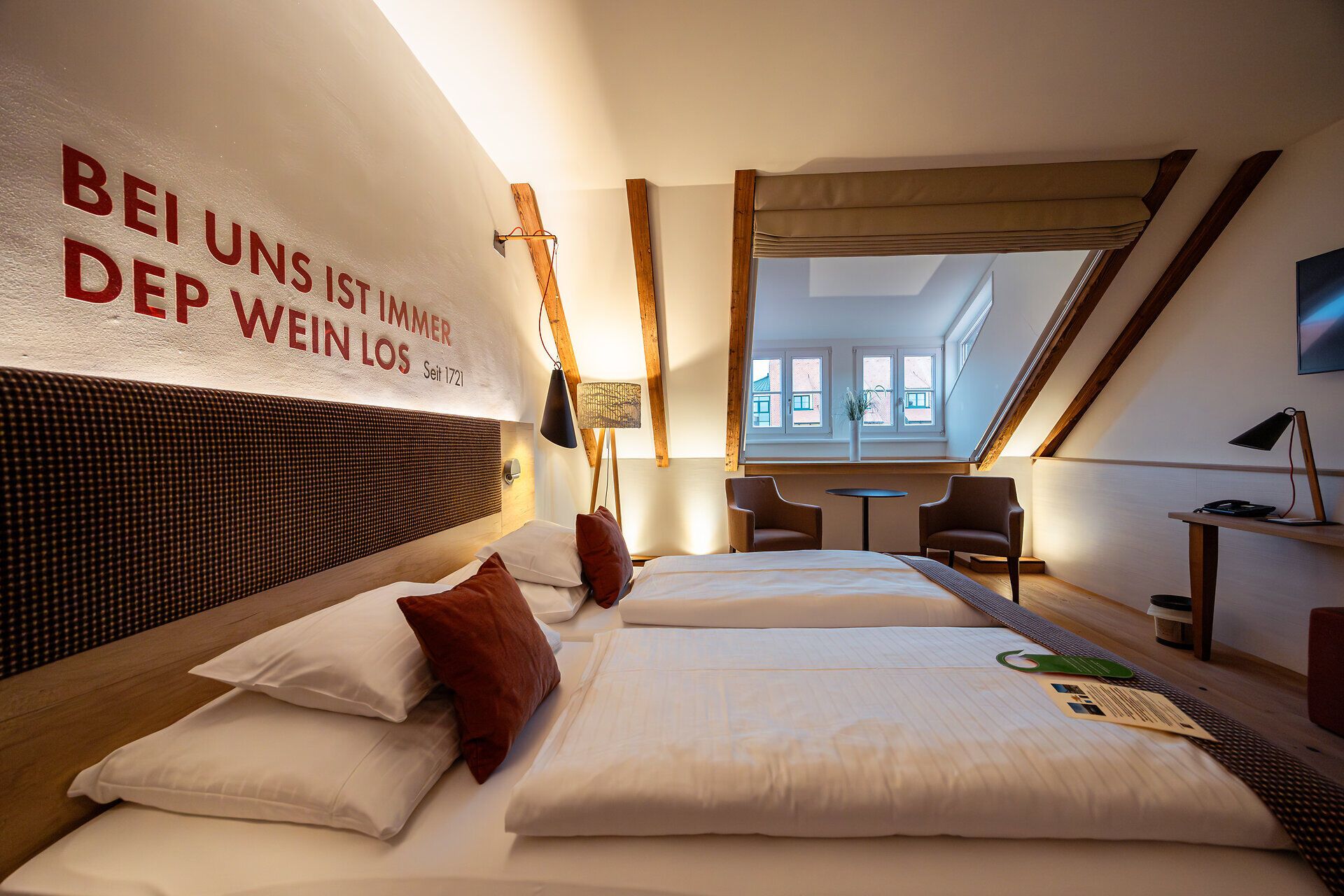 In einem stilvoll eingerichteten Zimmer mit warmen Holztönen und sanften Lichtakzenten lädt die gemütliche Atmosphäre zum Entspannen ein. Die großen Fenster bieten einen Blick auf die malerische Umgebung, während die geschmackvolle Dekoration die regionale Gastfreundschaft widerspiegelt.