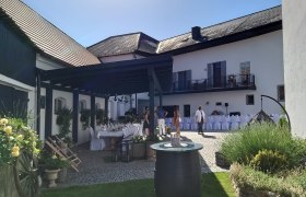 Innenhof mit gedeckten Tischen und dekorativen Pflanzen, sonniger Tag.