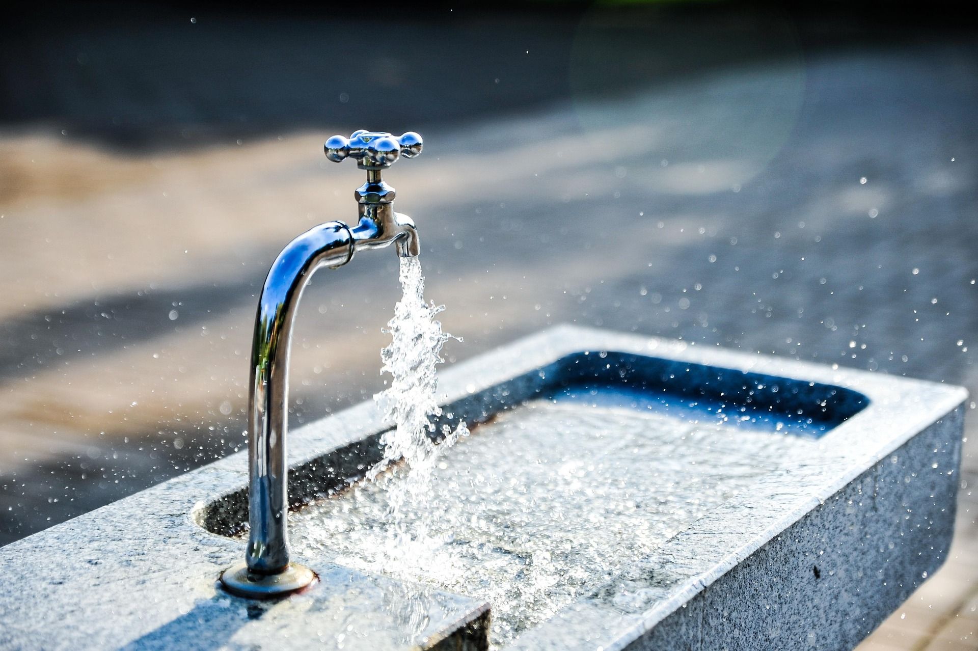 An outdoor drinking fountain with running water.