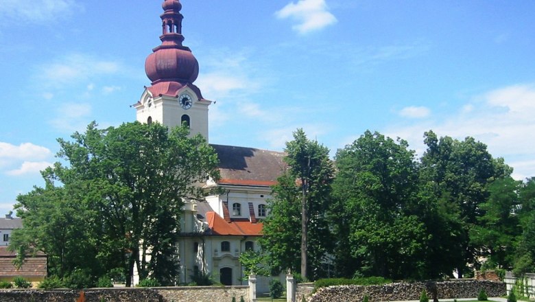 Barockkirche mit rotem Turm und Barockgarten im Vordergrund.