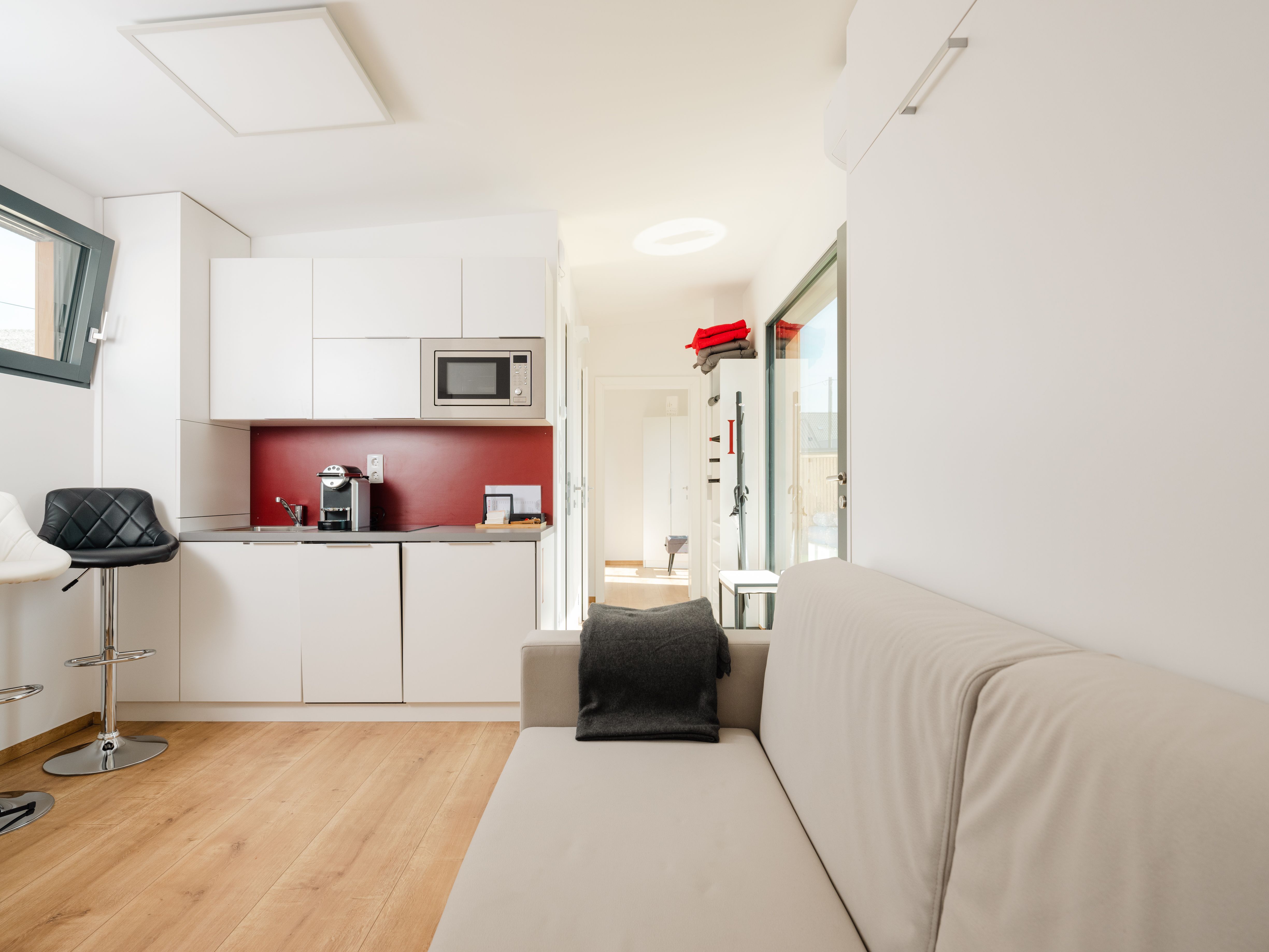 Moderne Wohnung mit Küchenzeile, Sofa und Barhocker.