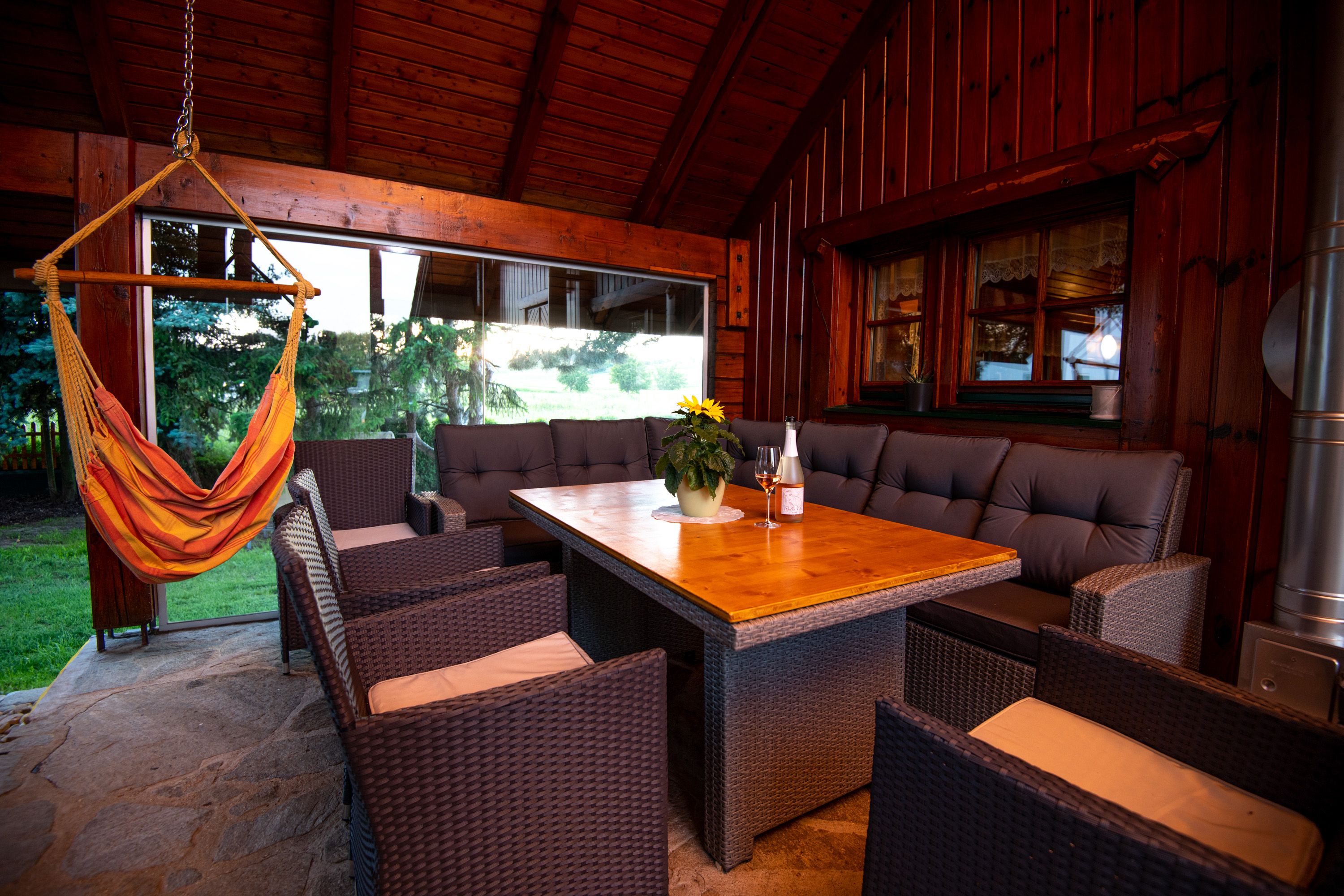 Überdachte Terrasse mit Holztisch, Rattanmöbeln und Hängesessel.