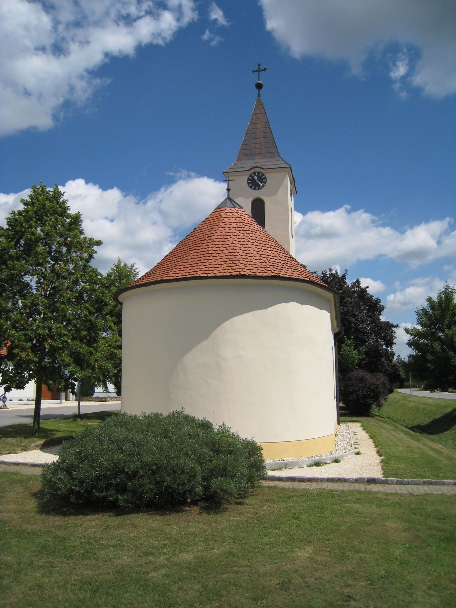 Kaple svaté Barbory s kulatou střechou a věží na pozadí modré oblohy.