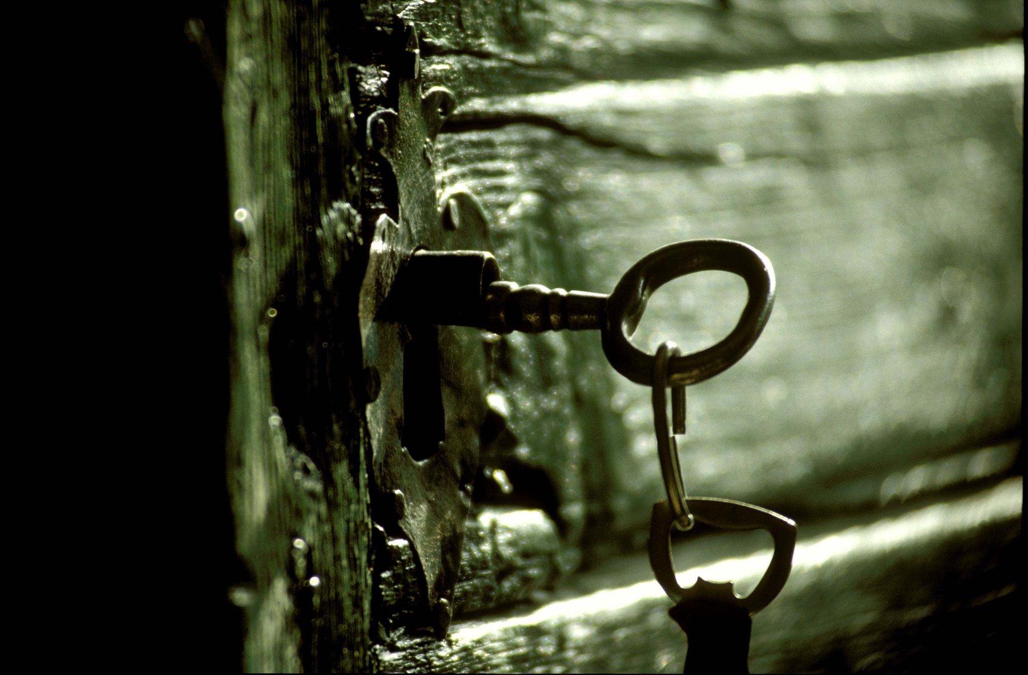 Ein alter Schlüssel steckt in einem antiken Schloss an einer Holztür.