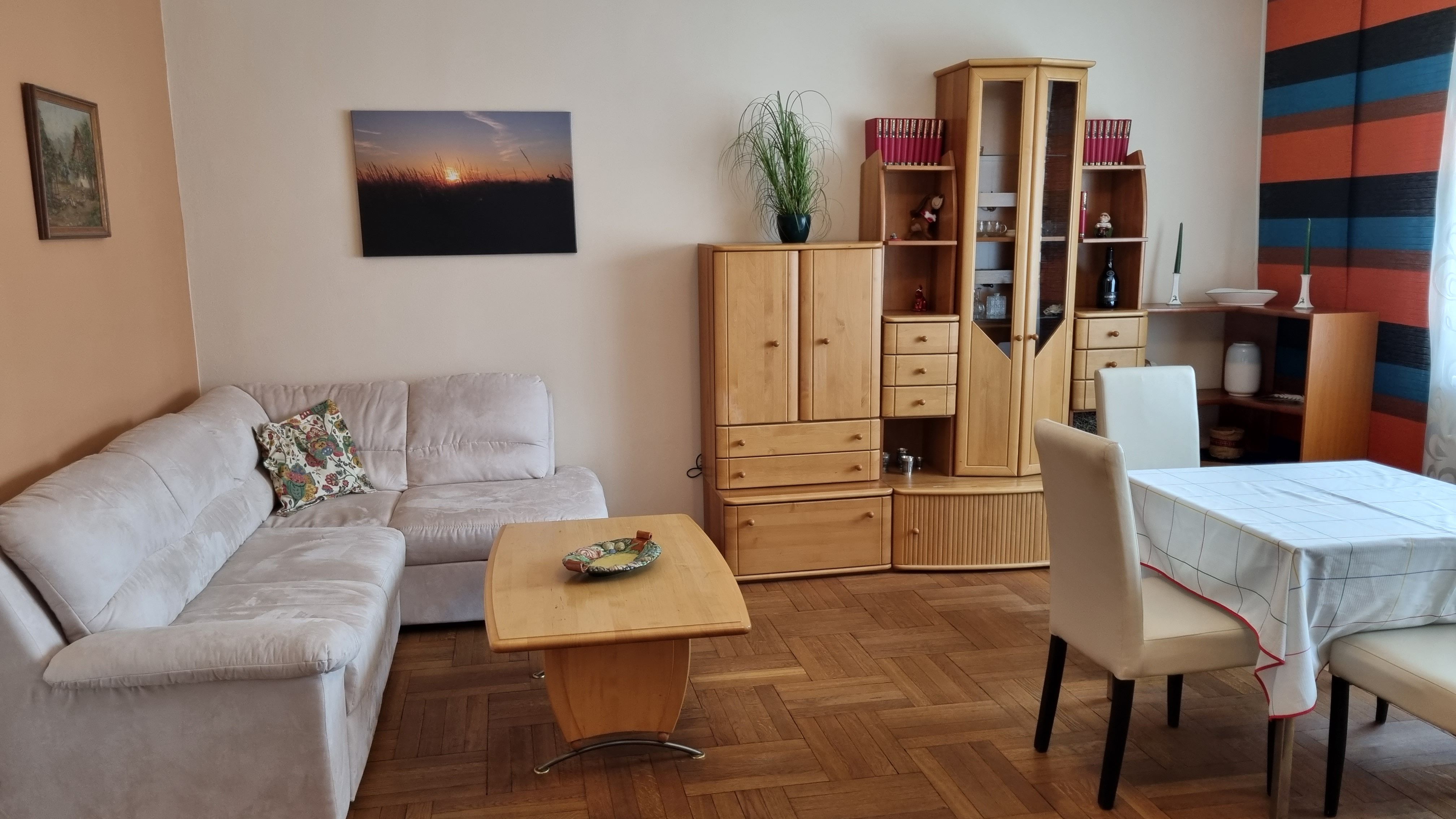Wohnzimmer mit beiger Couch, Holzmöbeln und Esstisch.