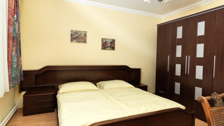 Ein gem&uuml;tliches Schlafzimmer mit einem Doppelbett, einem gro&szlig;en Kleiderschrank und zwei Bildern an der Wand.