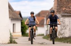 In der malerischen Kellergasse Maulavern radeln zwei begeisterte Radfahrer durch die idyllische Landschaft des Weinviertels. Umgeben von sanften Hügeln und üppigen Weinreben genießen sie die frische Luft und die Ruhe der Natur. Ein perfekter Tag für eine Entdeckungstour auf zwei Rädern.