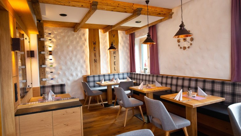 Gemütliches Restaurant mit Holzmöbeln, gedeckten Tischen und lila Vorhängen.