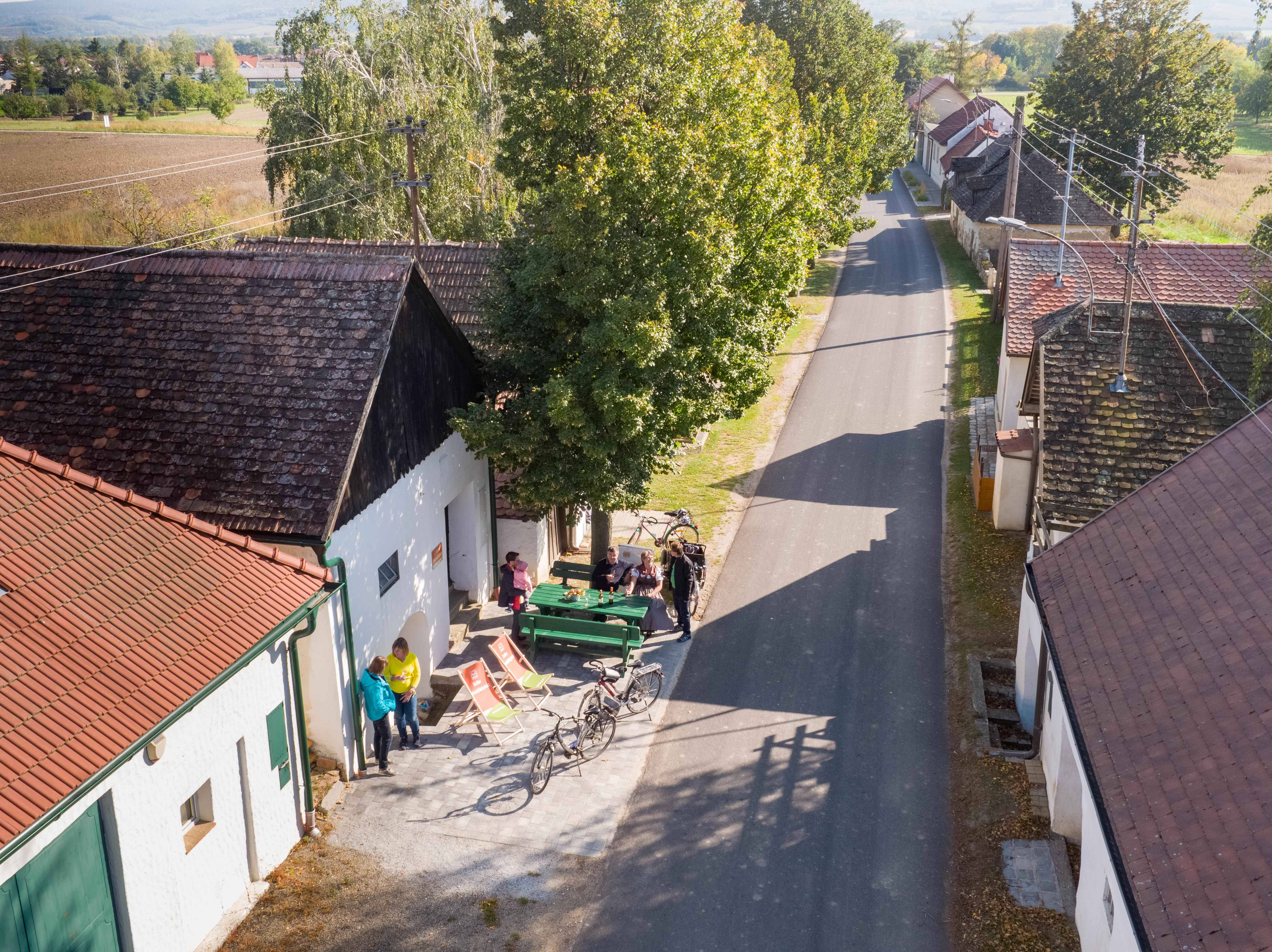 Luftaufnahme einer ländlichen Straße mit Menschen, Fahrrädern und Bäumen.