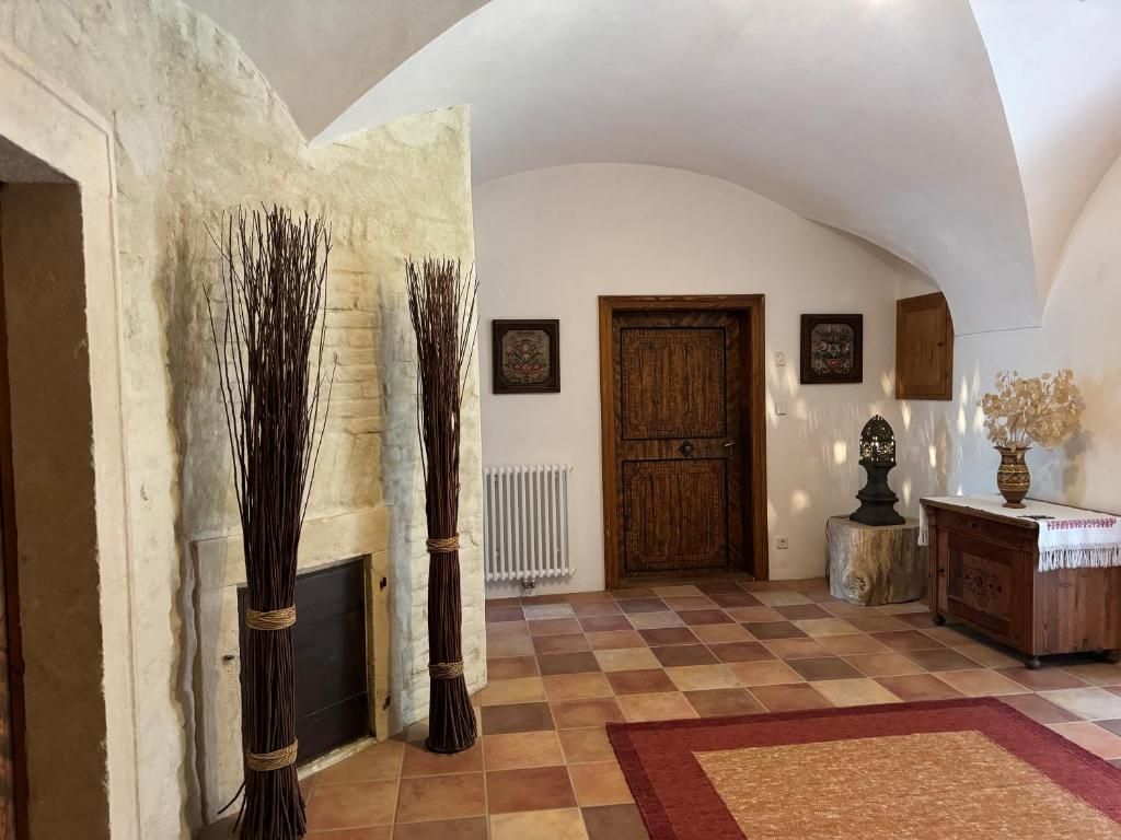 Rustikaler Eingangsbereich mit Holztür, Dekorationen und Fliesenboden.