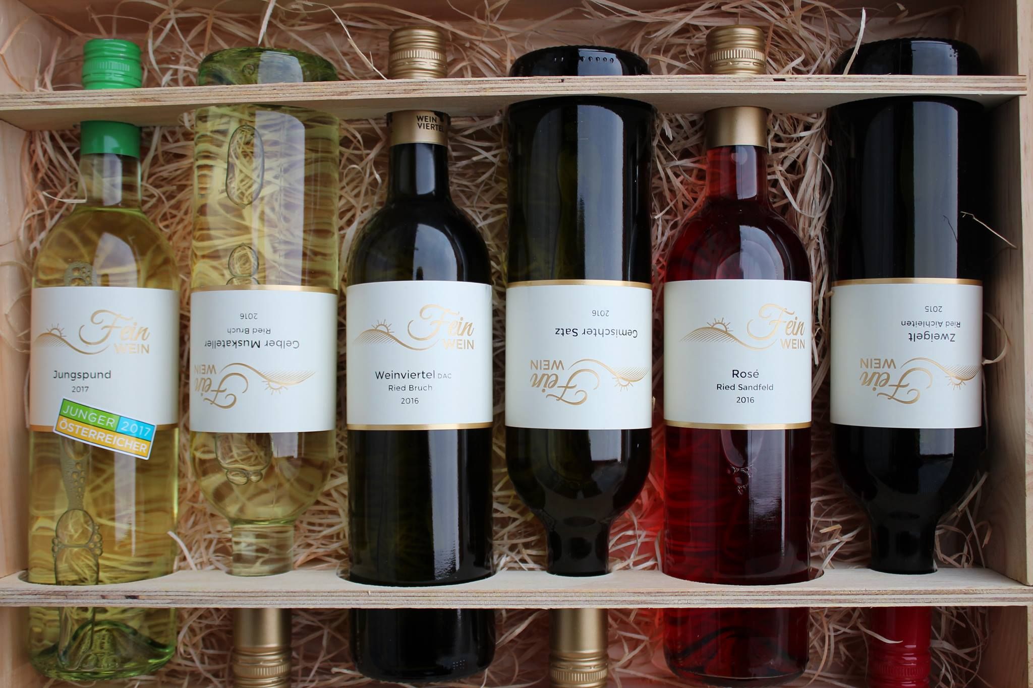 Six bottles of wine in a wooden crate with straw.