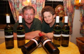 Zwei Personen hinter einem Tisch mit Weinflaschen.