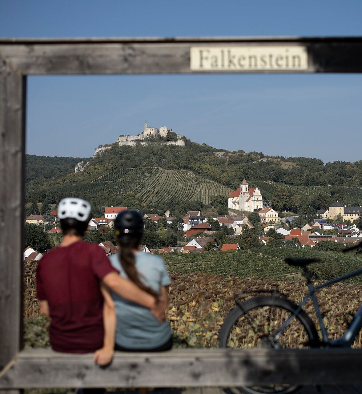 In der malerischen Landschaft genießen Radfahrer die atemberaubende Aussicht auf die sanften Hügel und das charmante Dorf. Die warmen Sonnenstrahlen und die frische Luft laden dazu ein, die Schönheit der Natur zu erkunden und unvergessliche Momente zu erleben.