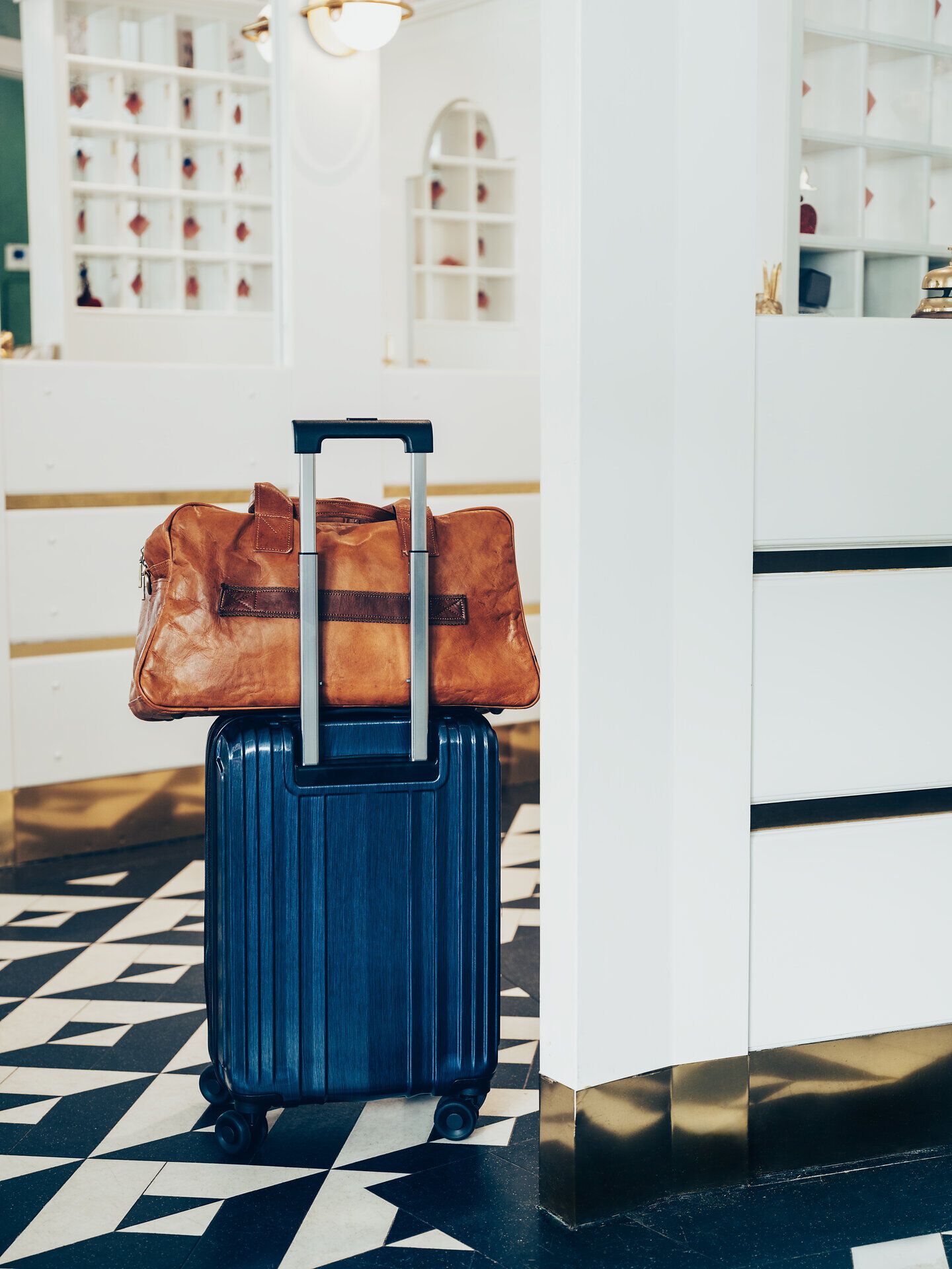 Ein eleganter Koffer und eine stilvolle Reisetasche stehen bereit, um die Abenteuer in den Wiener Alpen zu beginnen. Die helle, einladende Rezeption strahlt eine warme Atmosphäre aus, die Reisende dazu einlädt, die Schönheit der umliegenden Natur zu erkunden. Hier beginnt die Reise in eine Welt voller atemberaubender Ausblicke und unvergesslicher Erlebnisse.