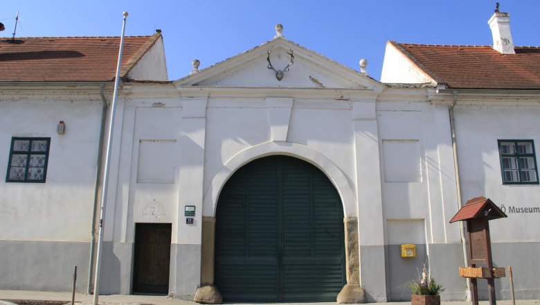 Historisches Gebäude mit großem Tor und Hirschgeweih an der Fassade.