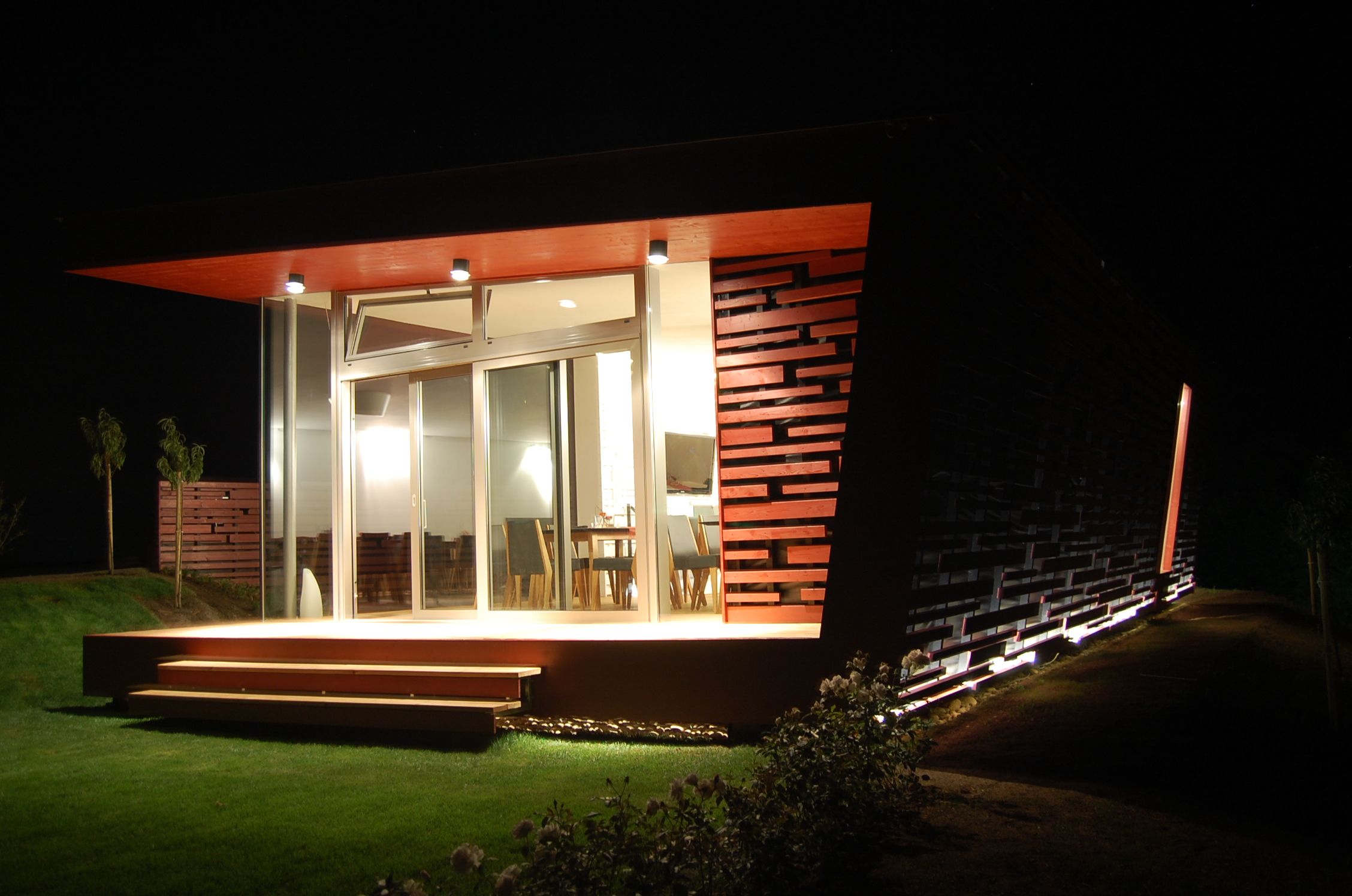 Modern building at night with illuminated terrace and glass front.