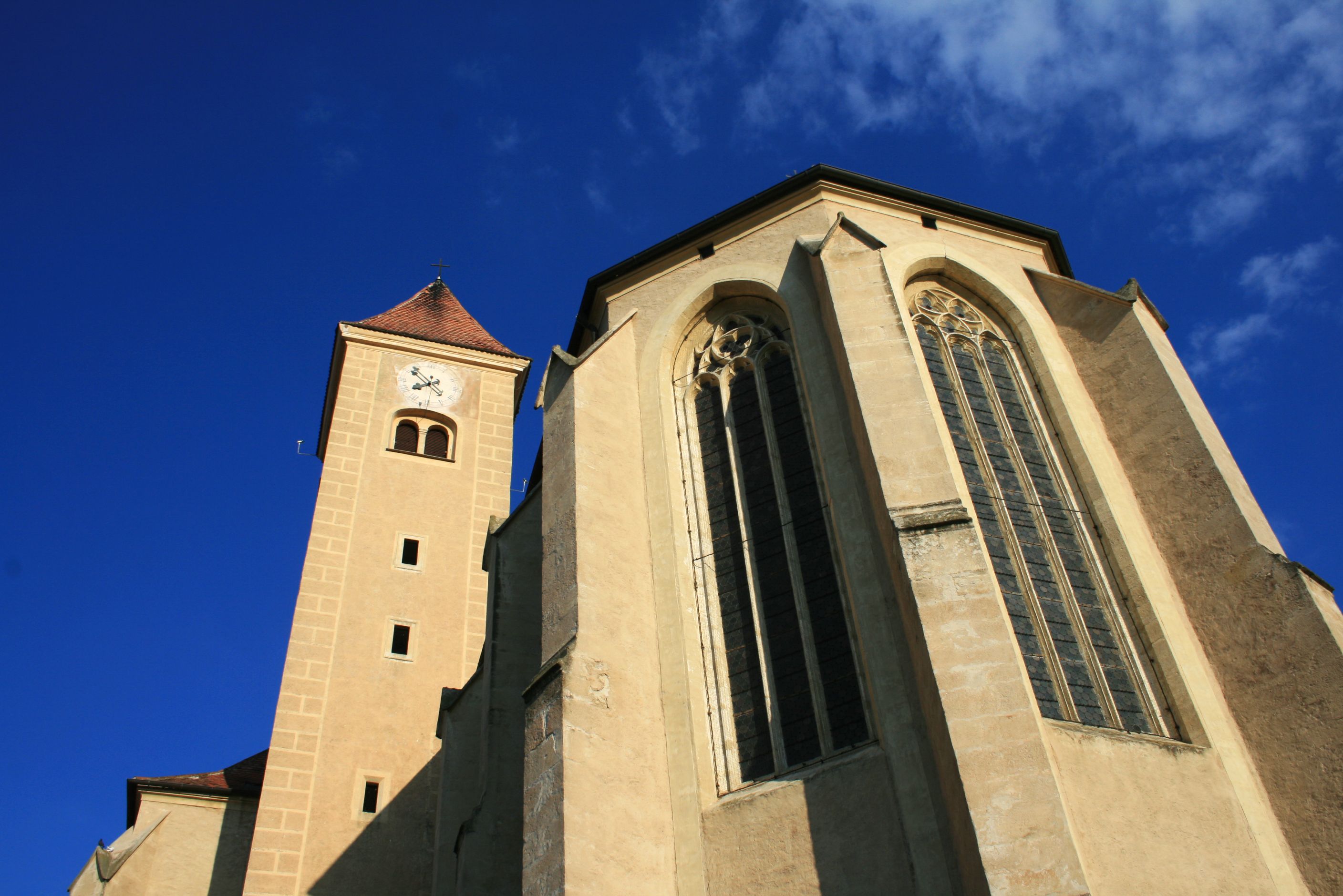 Ansicht der Hl. Blutkirche in Pulkau mit Turm und gotischen Fenstern vor blauem Himmel.