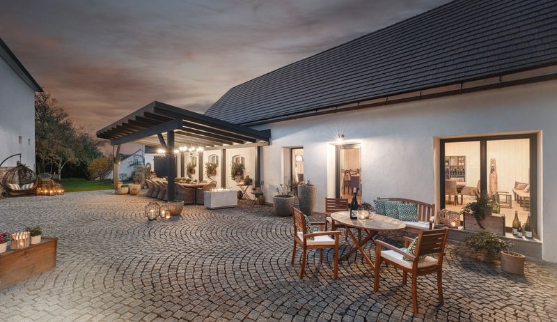 Gepflasterter Innenhof mit Tischen und Stühlen, umgeben von Gebäuden bei Abenddämmerung.