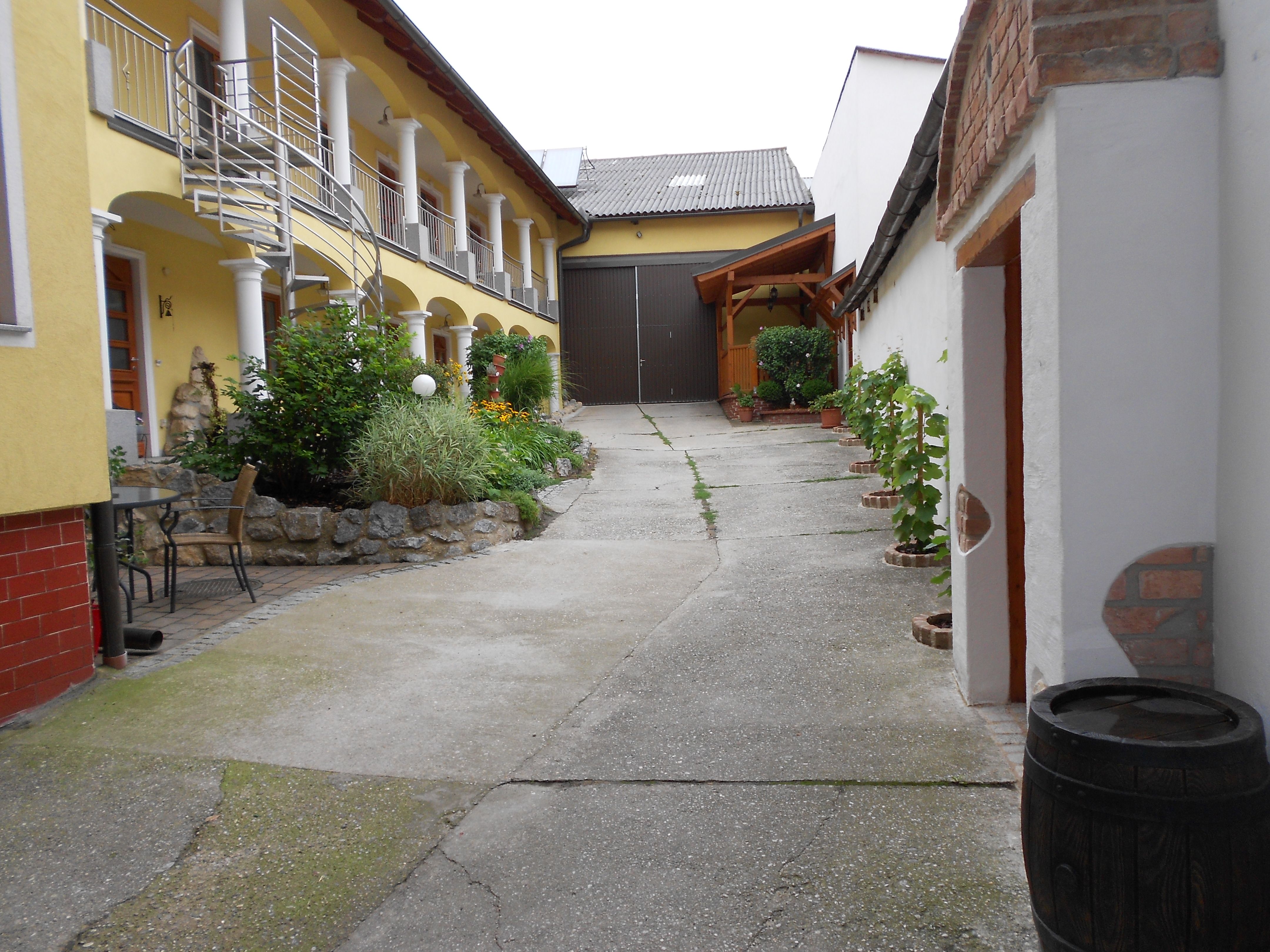 Ein Innenhof mit gelbem Gebäude, Pflanzen und einer Metalltreppe.
