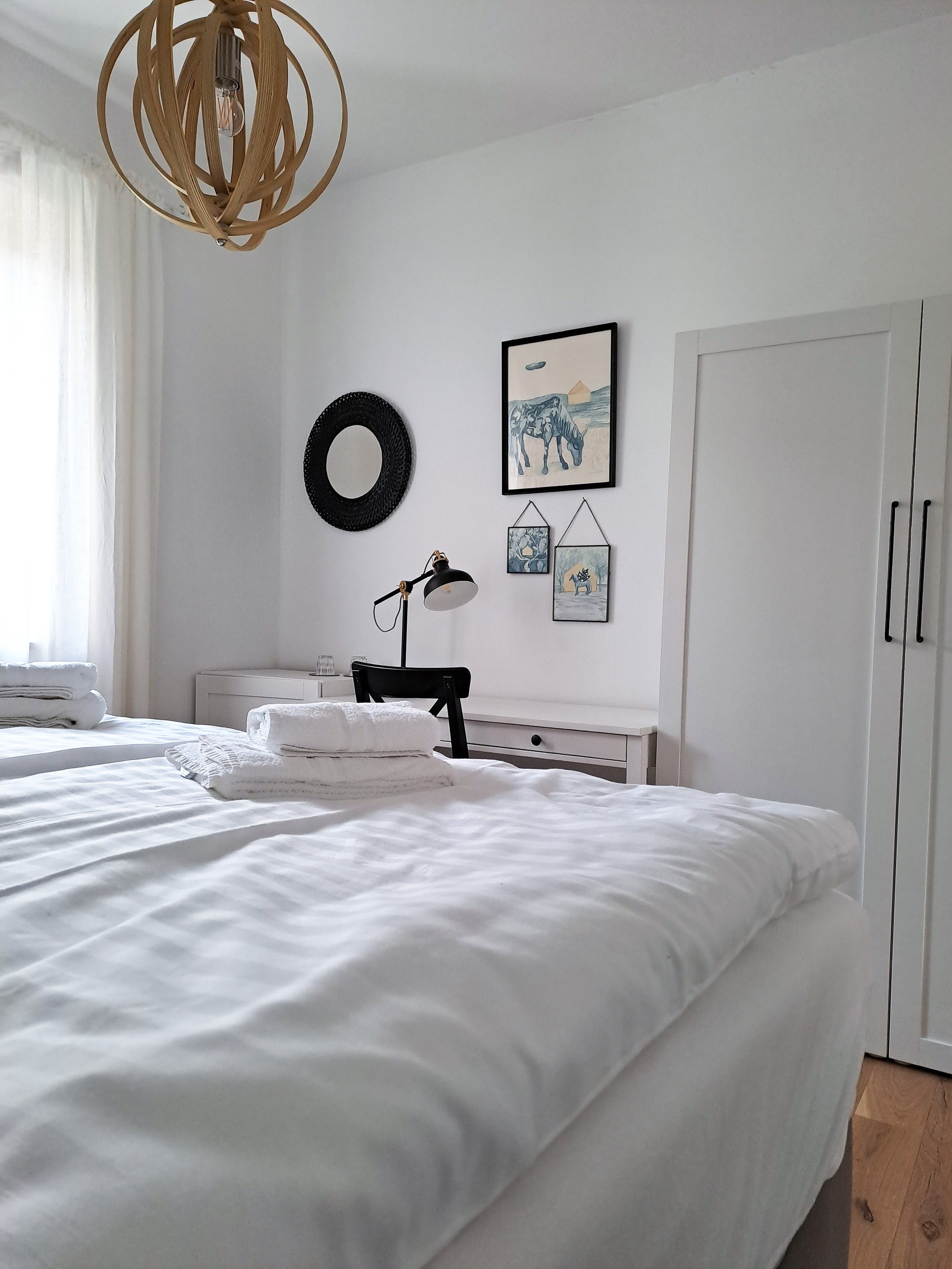 Bright bedroom with double bed, desk and wall decoration.