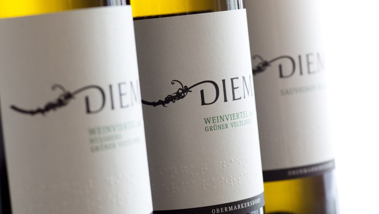 Nahaufnahme von Diem Weinflaschen mit Etiketten für Grüner Veltliner und Sauvignon Blanc.
