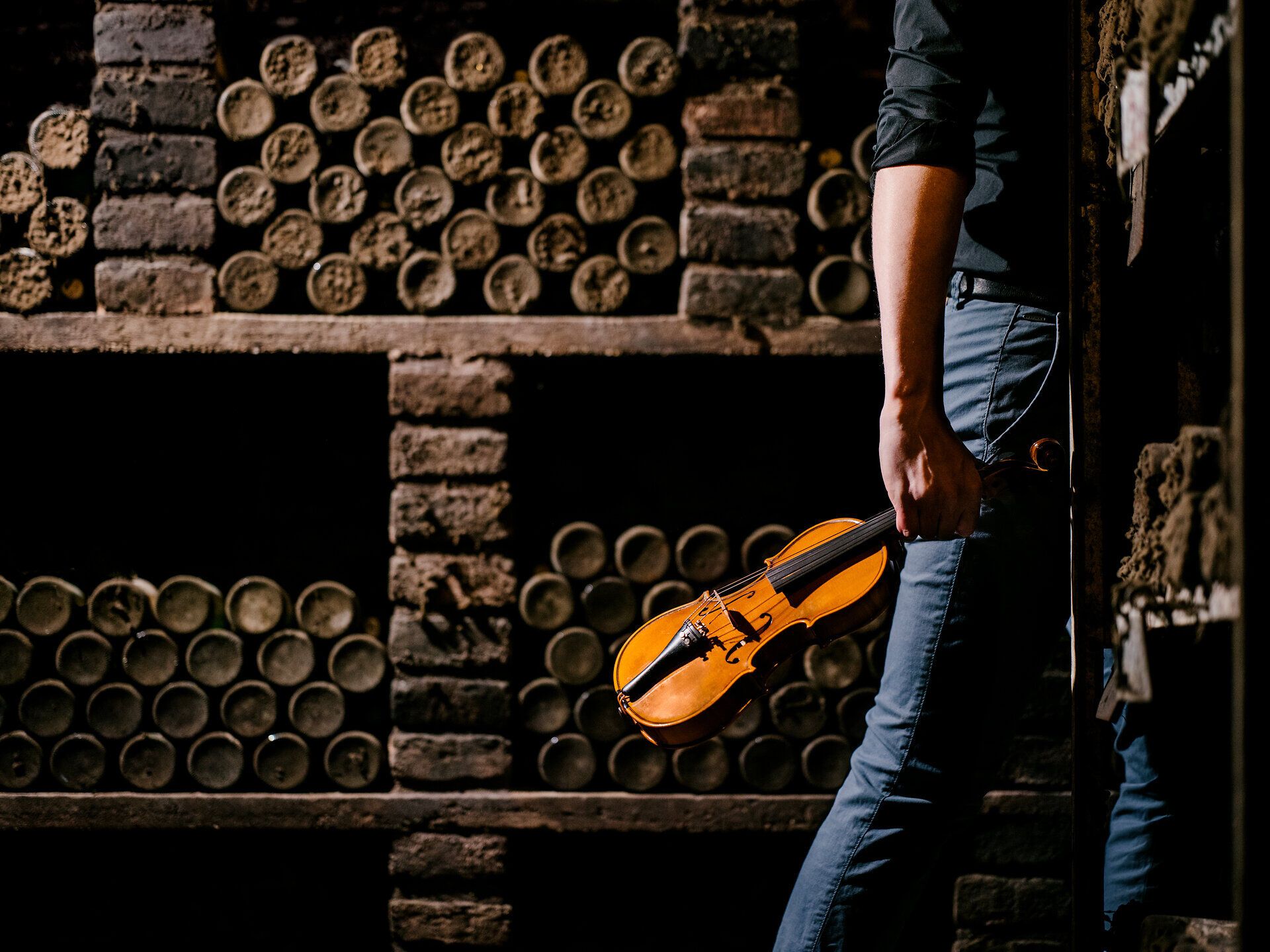 In einem stimmungsvollen Weinkeller, umgeben von alten Holzfässern, wird die Melodie einer Geige gespielt. Die sanften Klänge vermischen sich mit dem Duft des Weins und schaffen eine Atmosphäre der Gemütlichkeit und Tradition. Hier erleben Besucher die harmonische Verbindung von Kultur und Genuss.