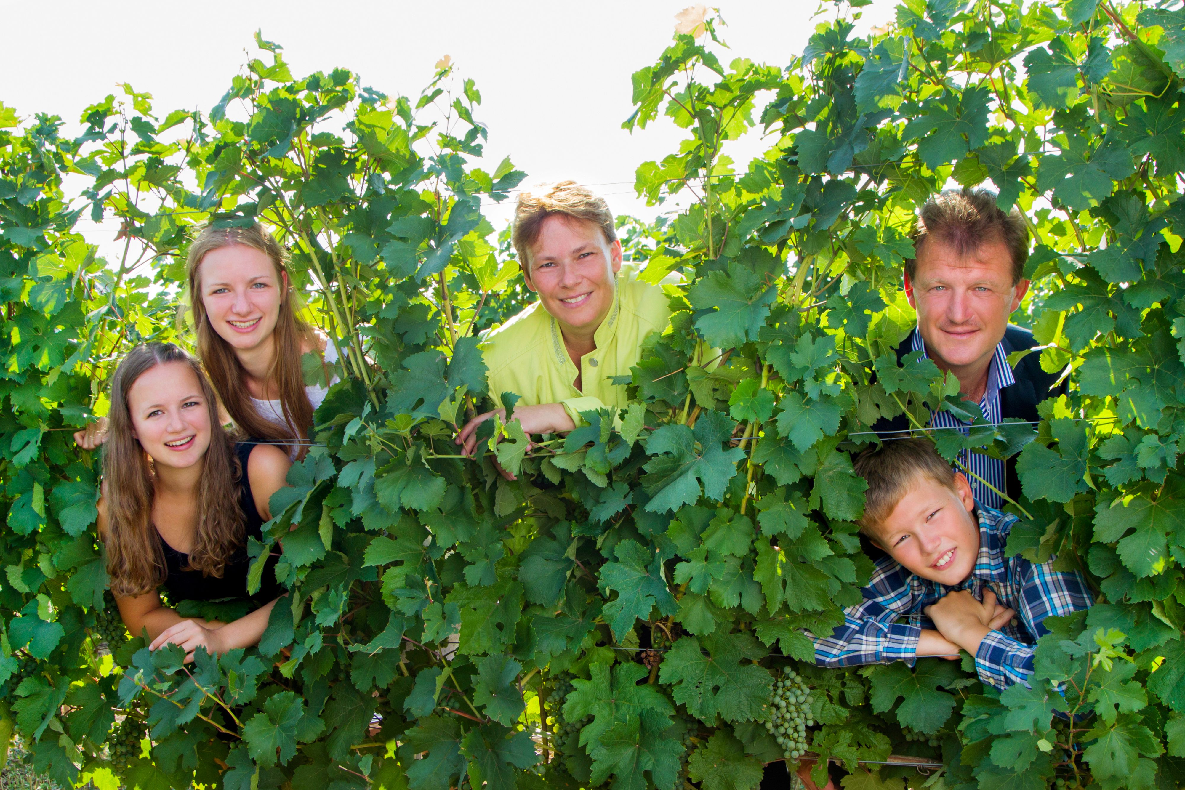 A family looks through vines with a smile.