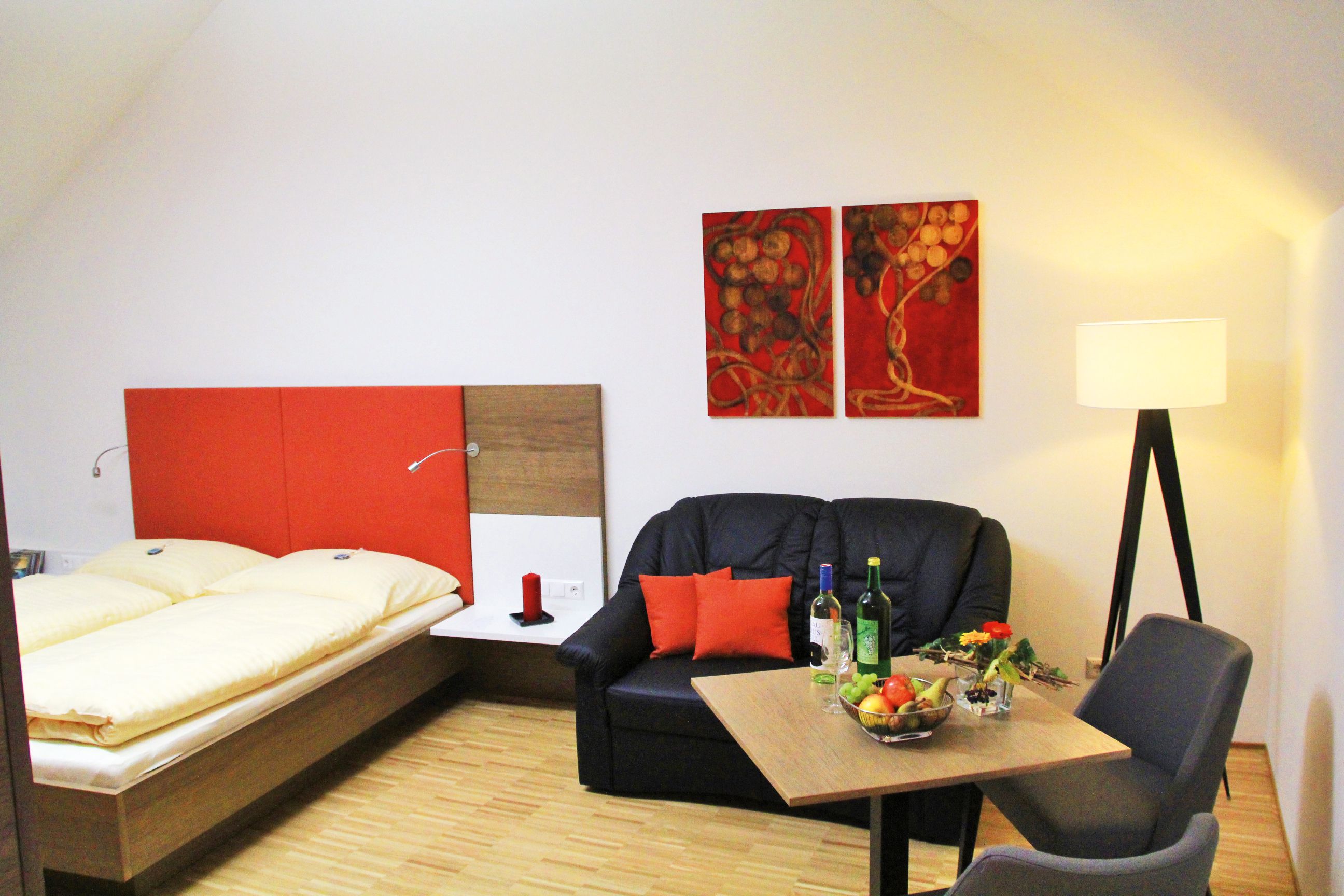 Gemütliches Zimmer mit Doppelbett, Sofa, Tisch und Stehlampe.