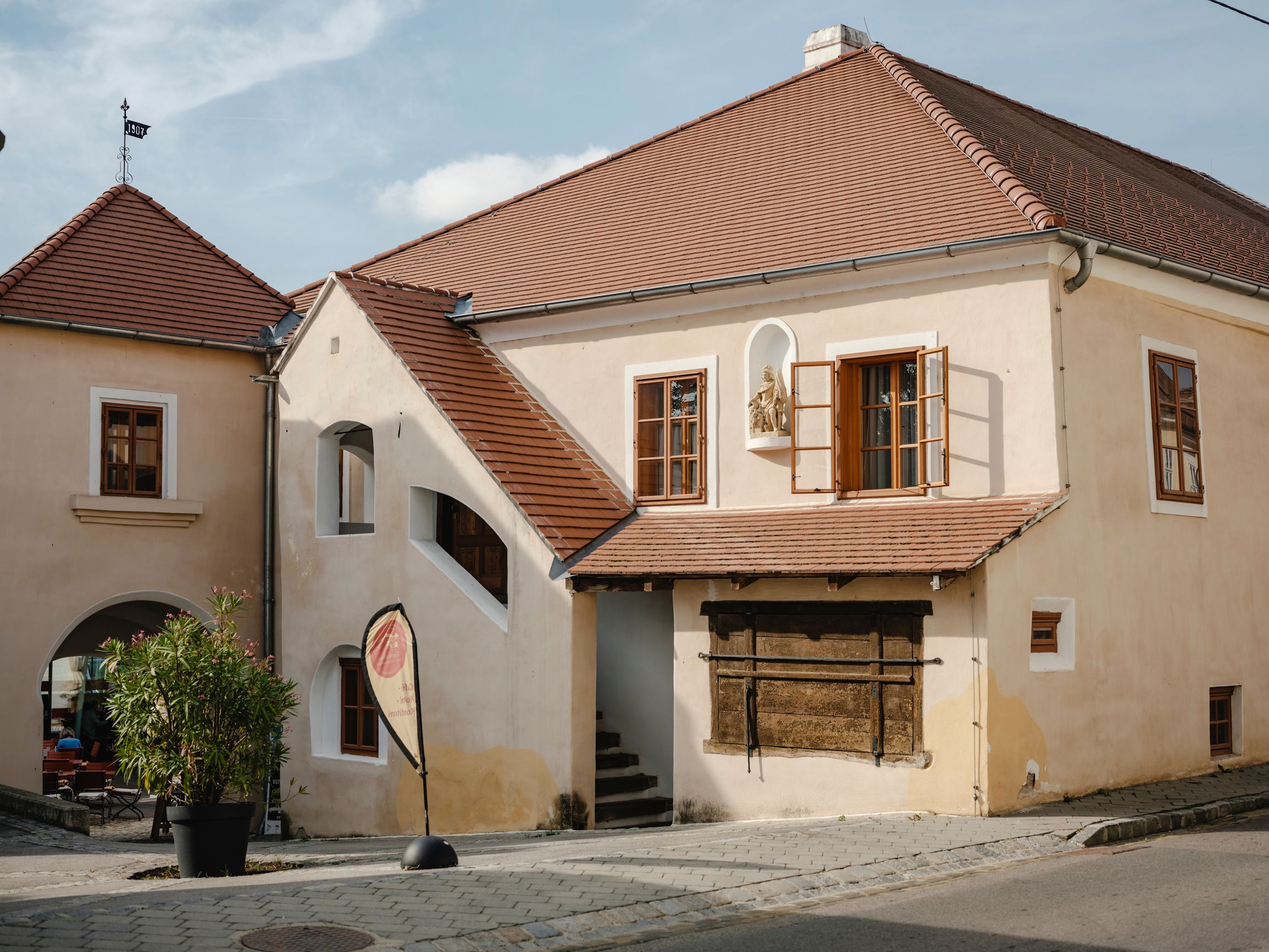 Historisches Gebäude mit roten Ziegeldächern und offenen Fenstern.