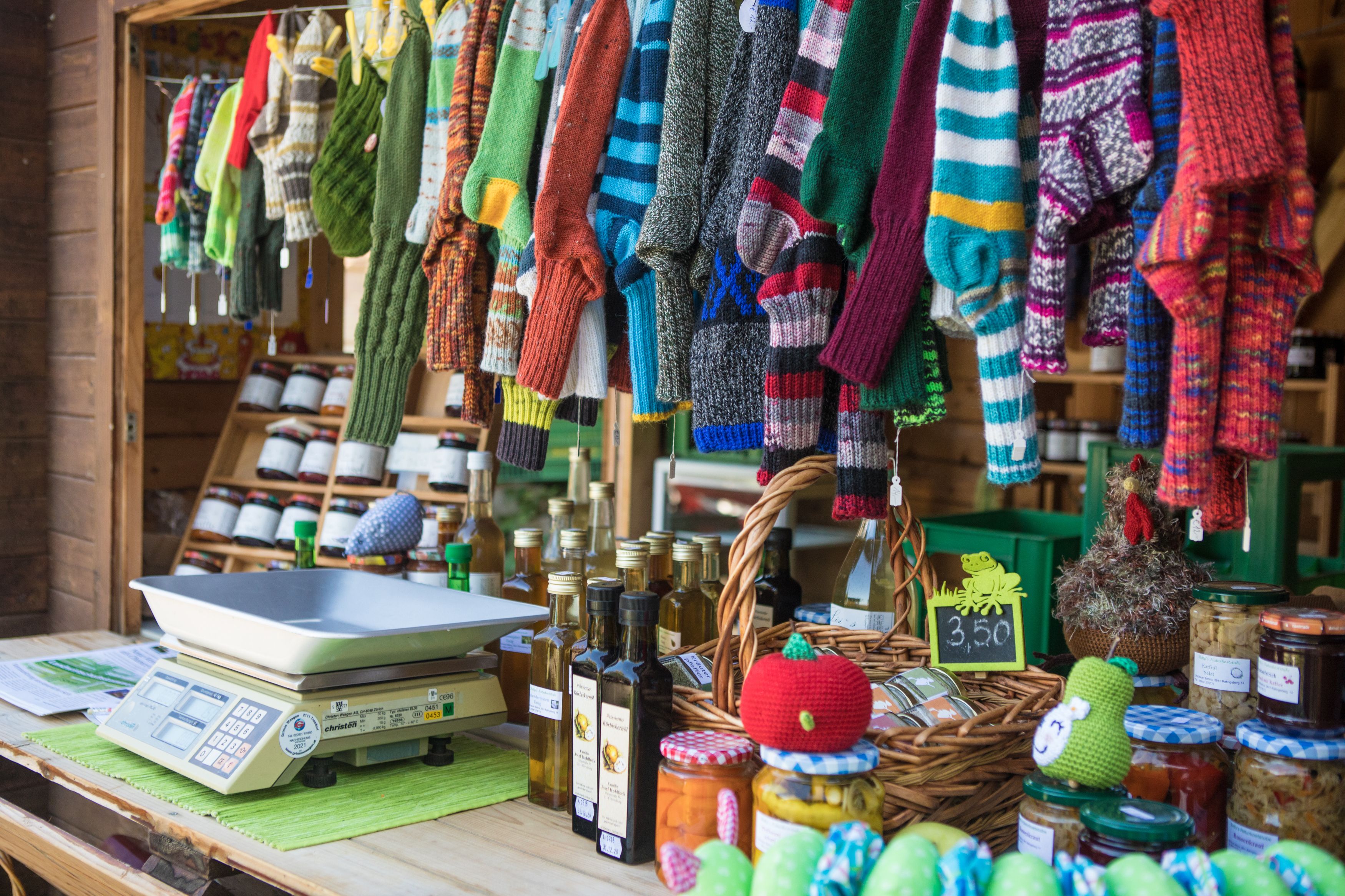 Marktstand mit gestrickten Socken, Ölflaschen und Einmachgläsern.