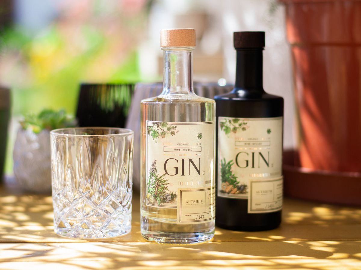 Two bottles of gin and a glass on a table outside.