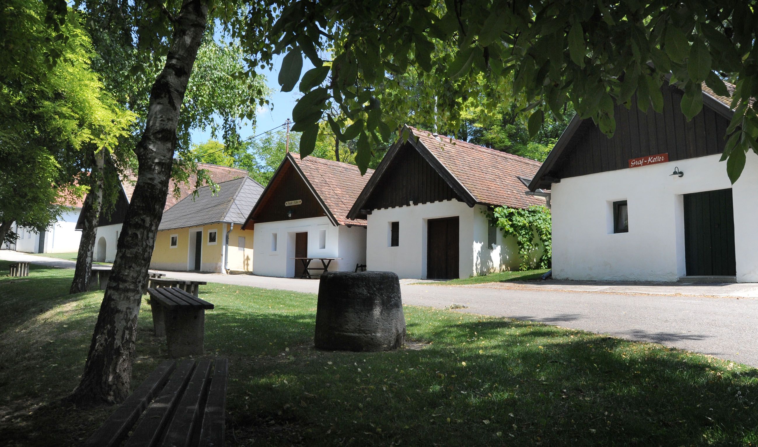Eine malerische Kellergasse mit traditionellen Weinkellern und grüner Umgebung in Zellerndorf.