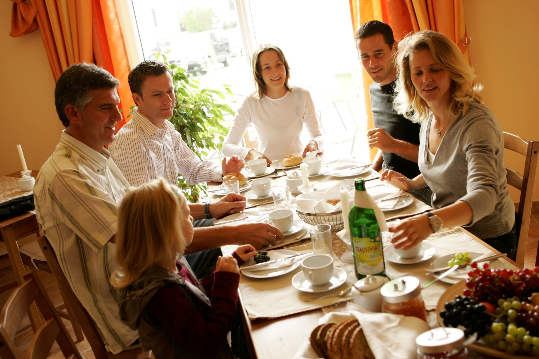 Eine Gruppe von Menschen sitzt an einem Tisch und genießt ein gemeinsames Frühstück.