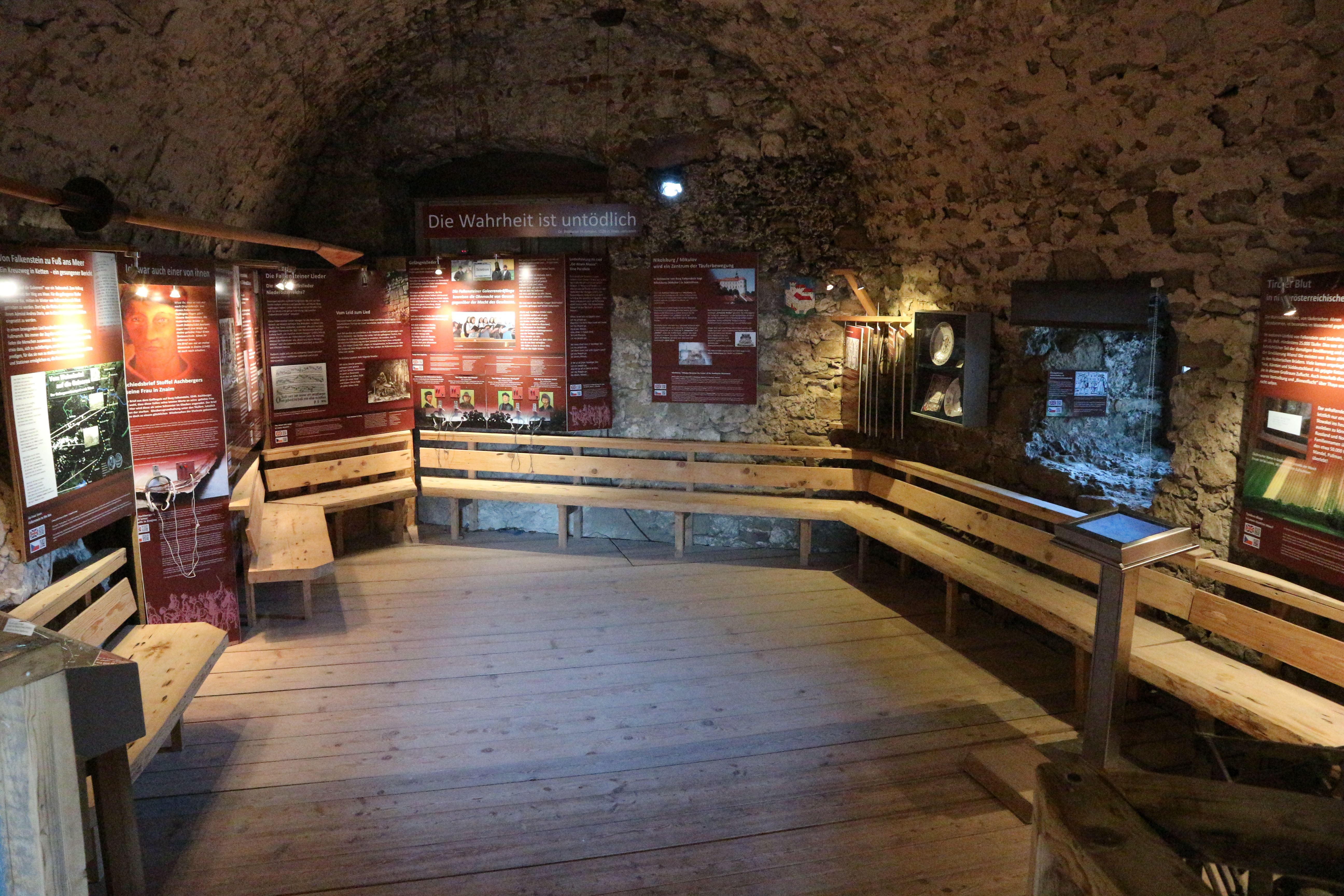 Historischer Raum mit Infotafeln und Holzbänken.