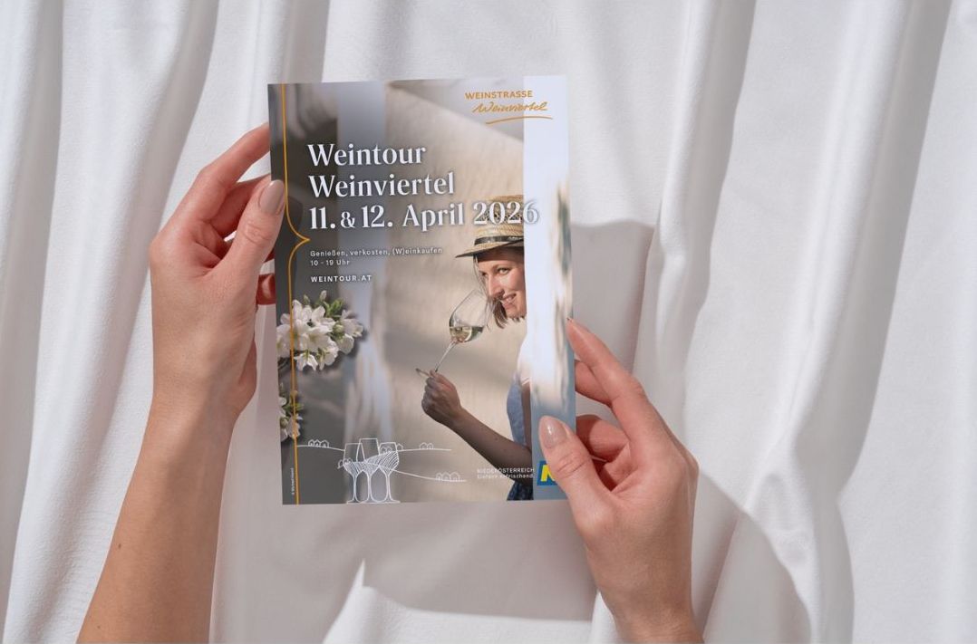 Zwei Hände halten ein Prospekt mit dem Titel Weintour Weinviertel.