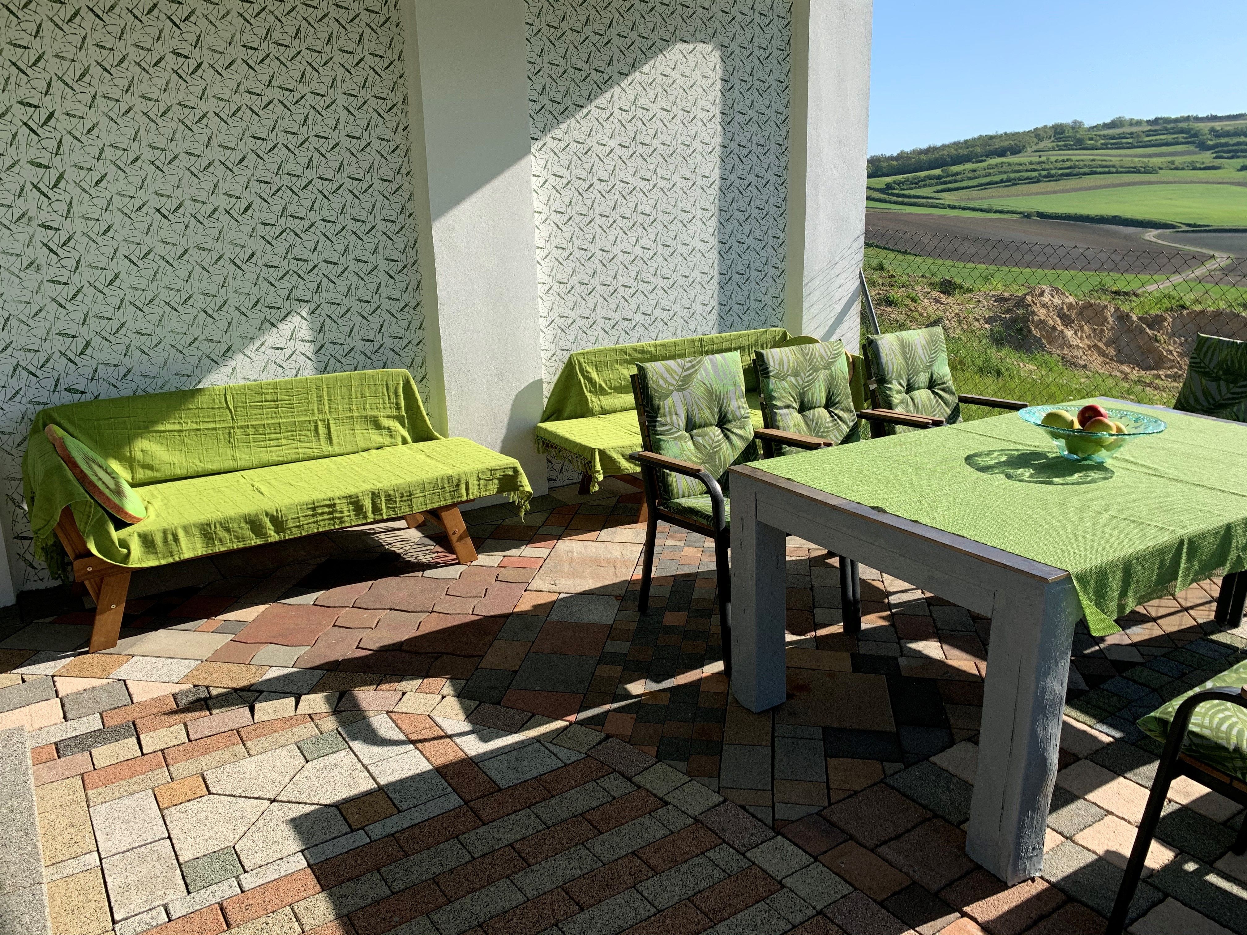 Terrasse mit grünen Möbeln und Blick auf Felder.