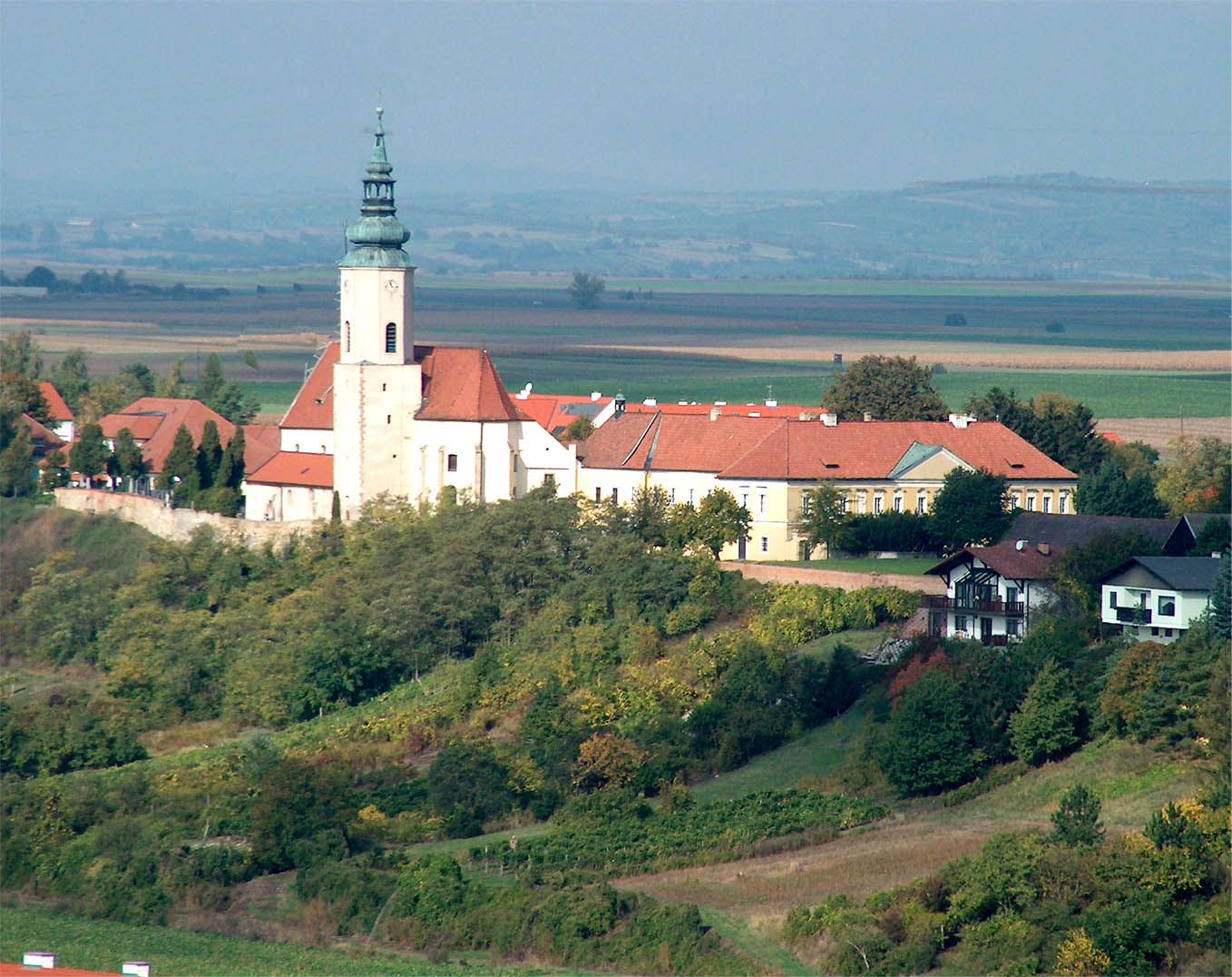 Luftbild der Pfarrkirche St. Agatha in einer ländlichen Umgebung mit umliegenden Gebäuden und Feldern.