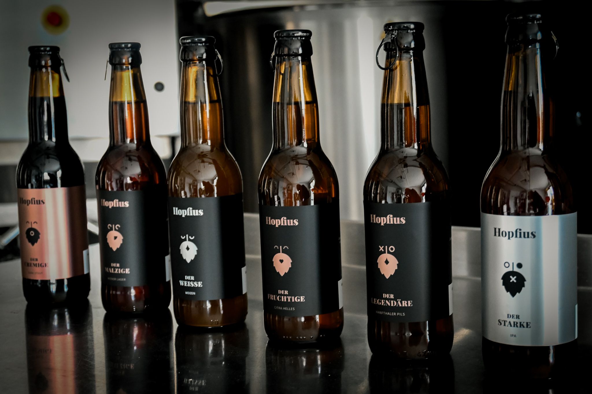 Sechs Bierflaschen der Marke Hopflius auf einem Tisch.