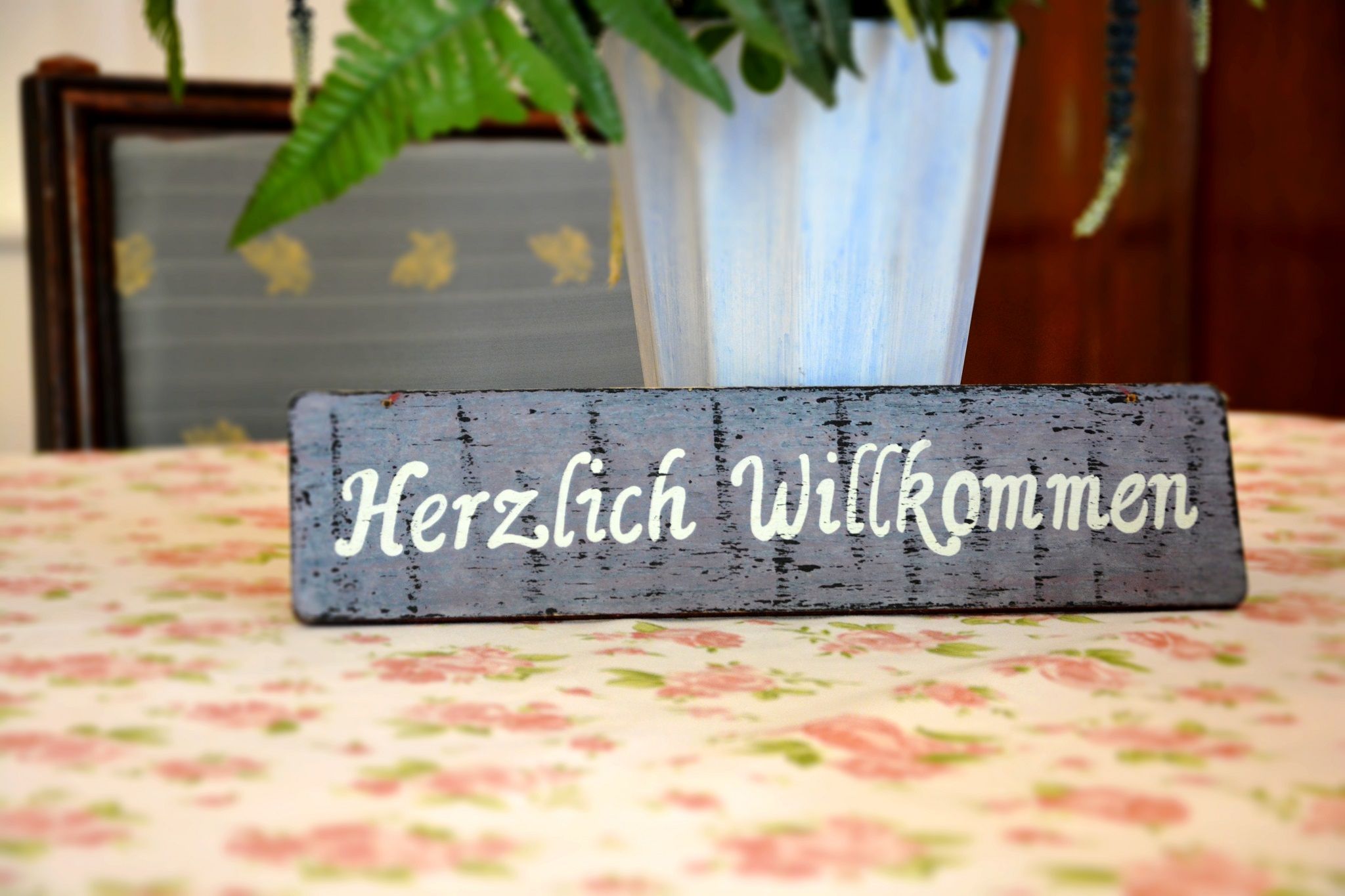 A wooden sign with the inscription 'Welcome' stands on a flowery table.