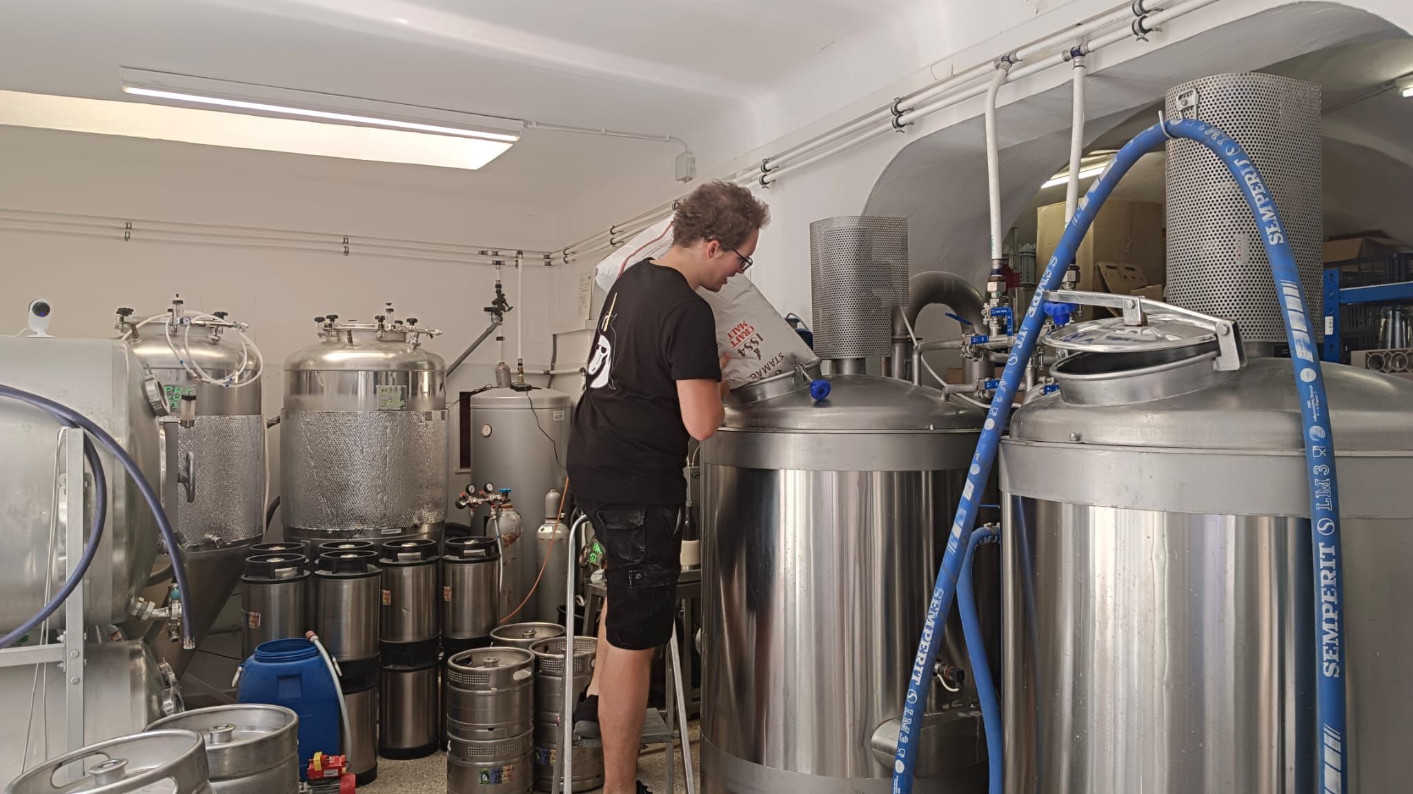 Person working on a brewing kettle in a brewery.