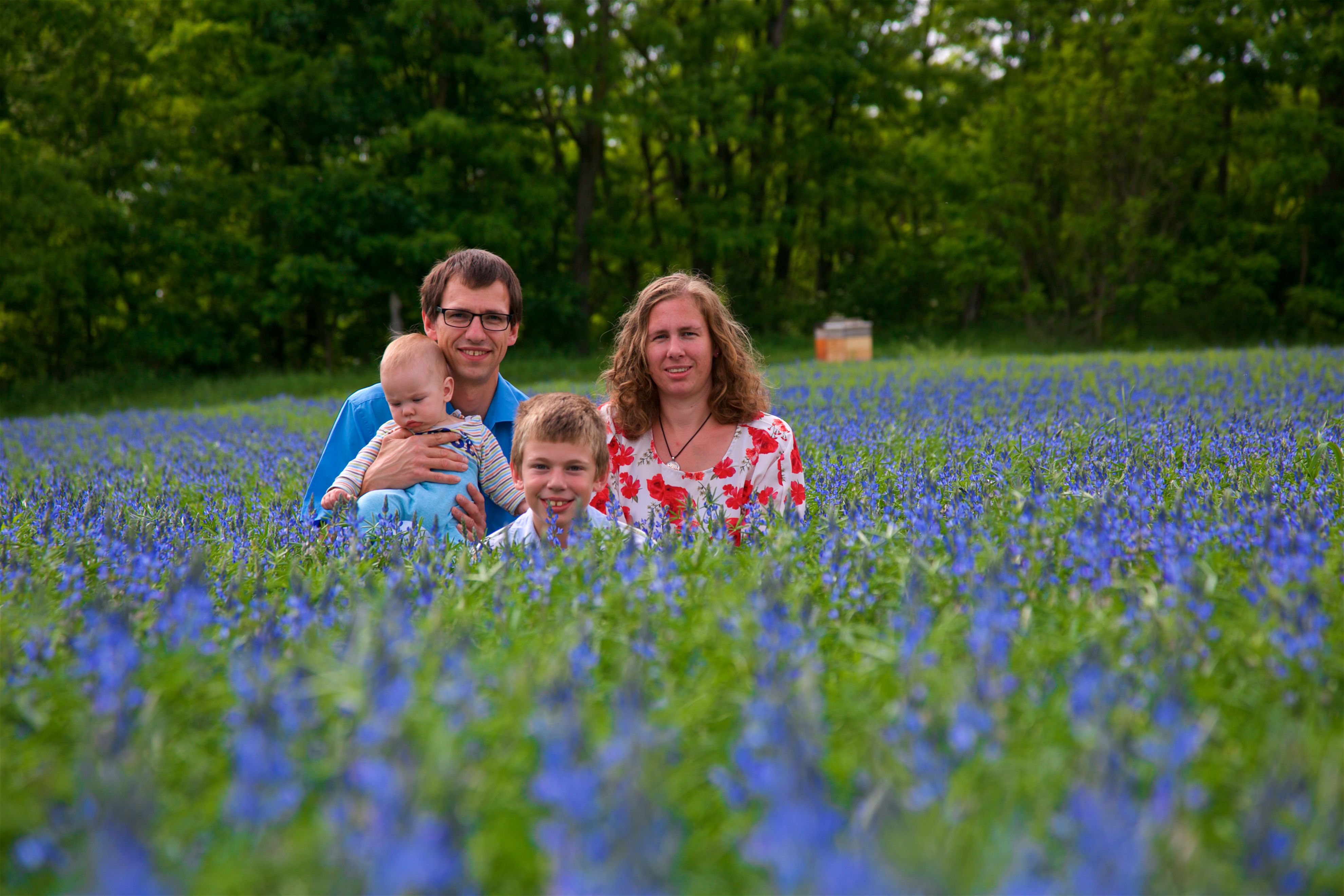 Eine Familie (zwei Erwachsene, zwei Kinder) posiert in einem Feld.