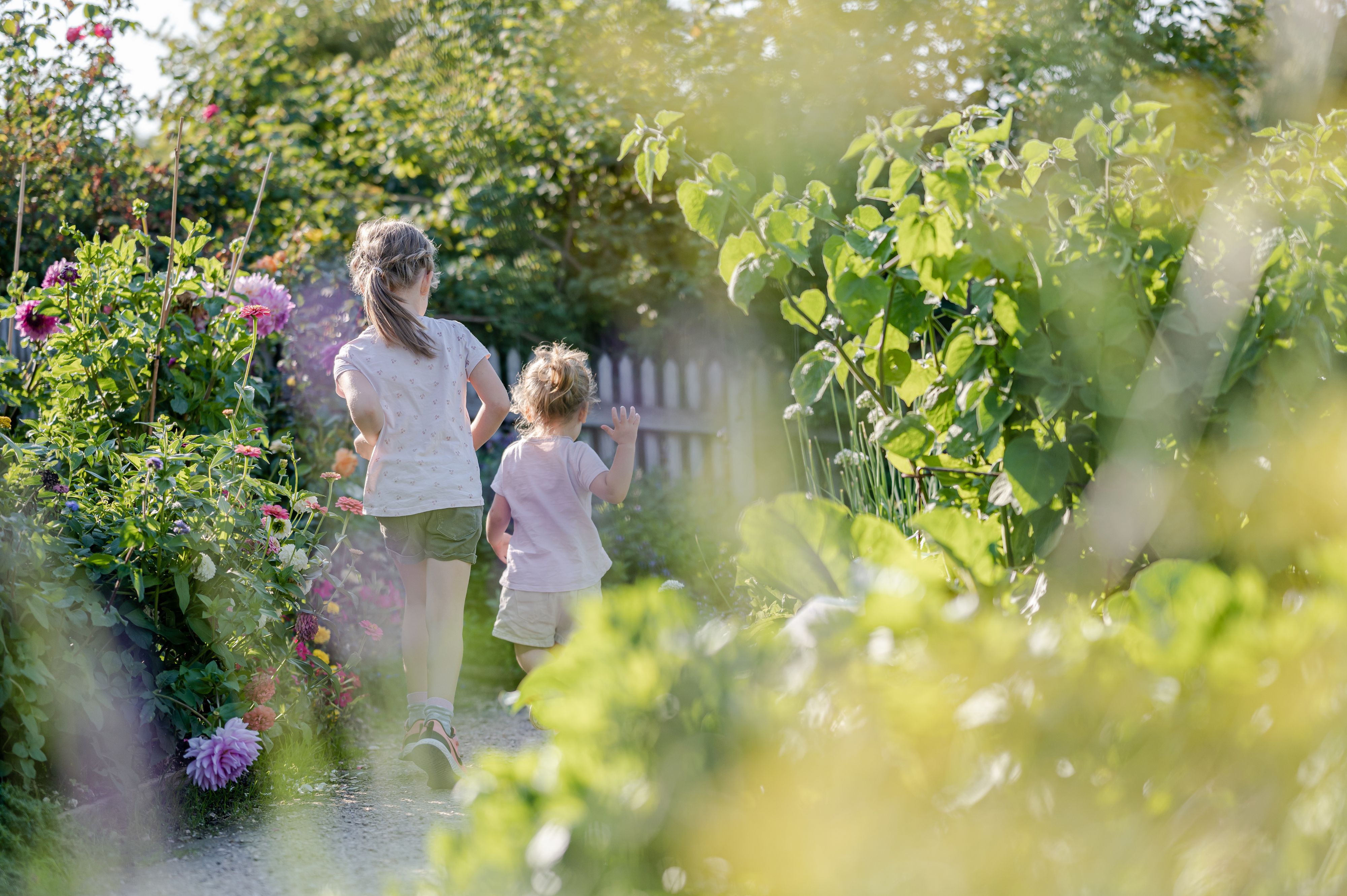 Two children run through a flowering garden path in the museum village of Niedersulz.