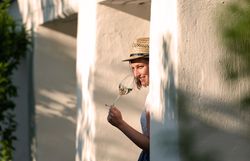 Eine Frau mit Strohut riecht an einem Glas Weißwein.