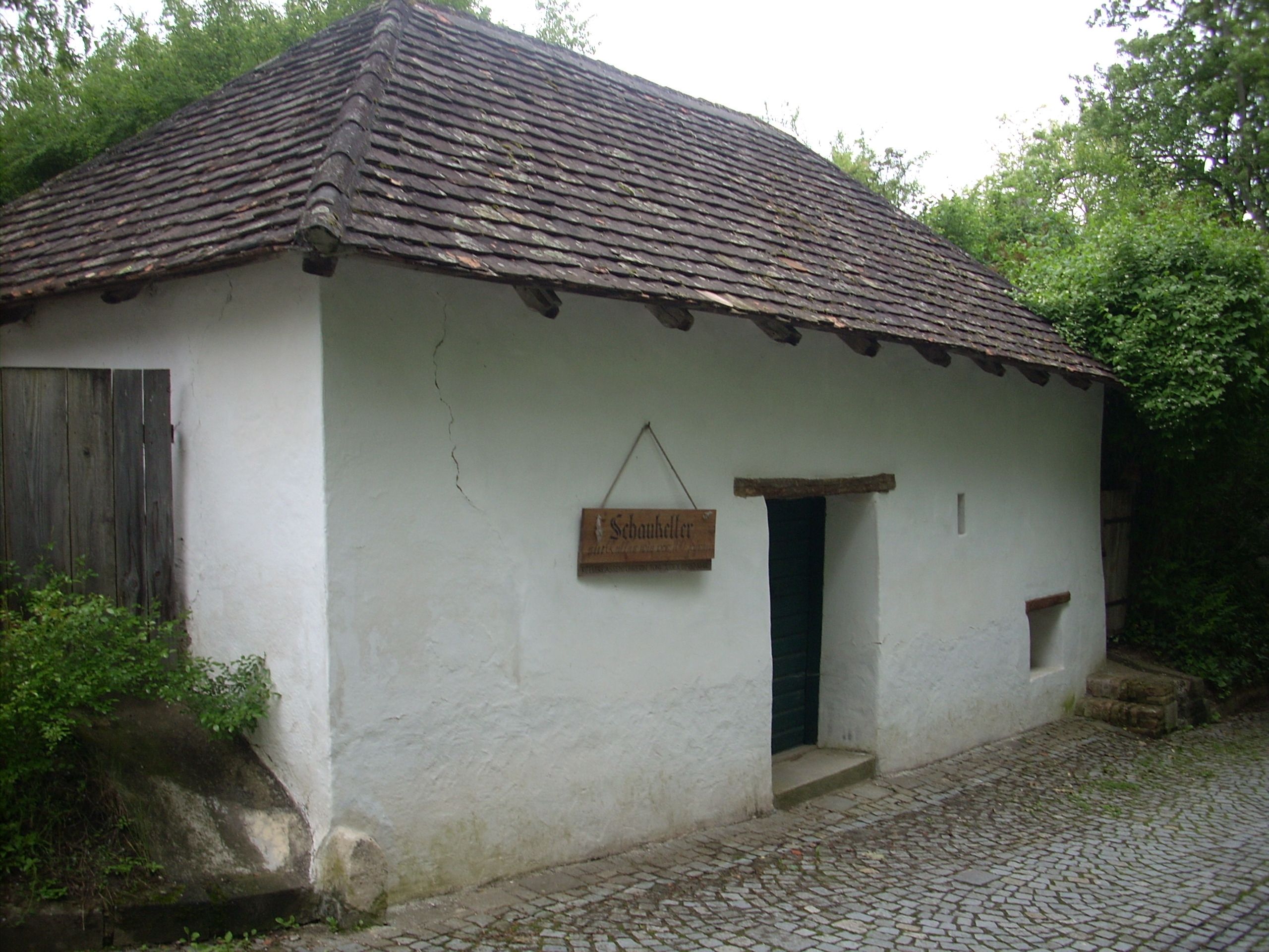 Ein traditionelles Gebäude mit weißer Fassade und Ziegeldach, beschriftet als 'Schaukeller'.