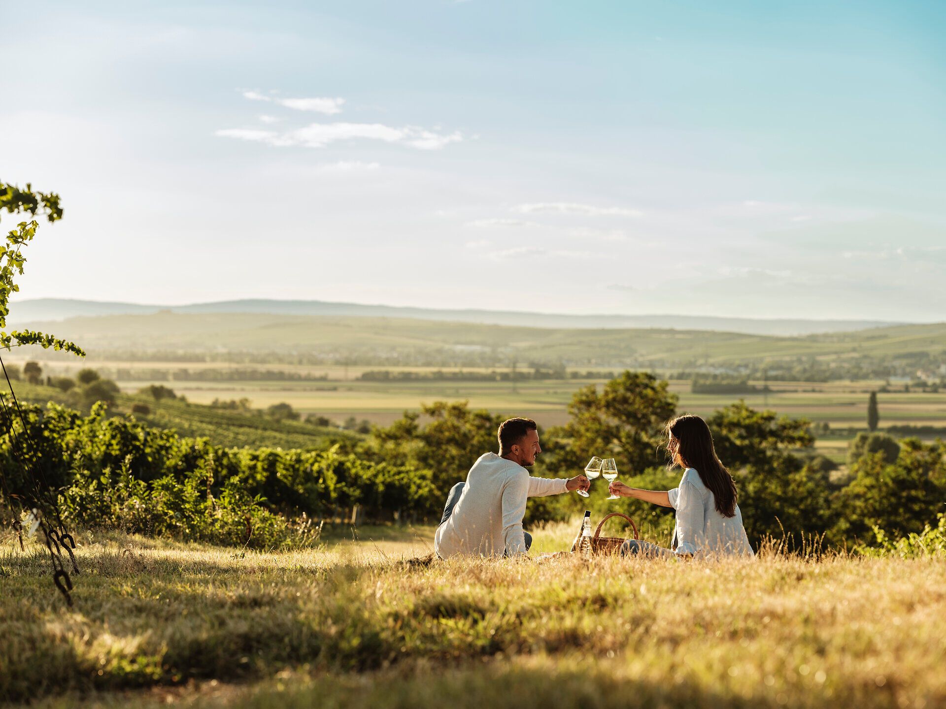 Ein romantisches Picknick inmitten der sanften Hügel des Weinviertels lädt dazu ein, die Seele baumeln zu lassen. Umgeben von üppigen Weinreben und der warmen Abendsonne genießen die beiden Gäste köstlichen Wein und regionale Spezialitäten. Diese idyllische Szenerie verspricht unvergessliche Momente der Entspannung und des Genusses.